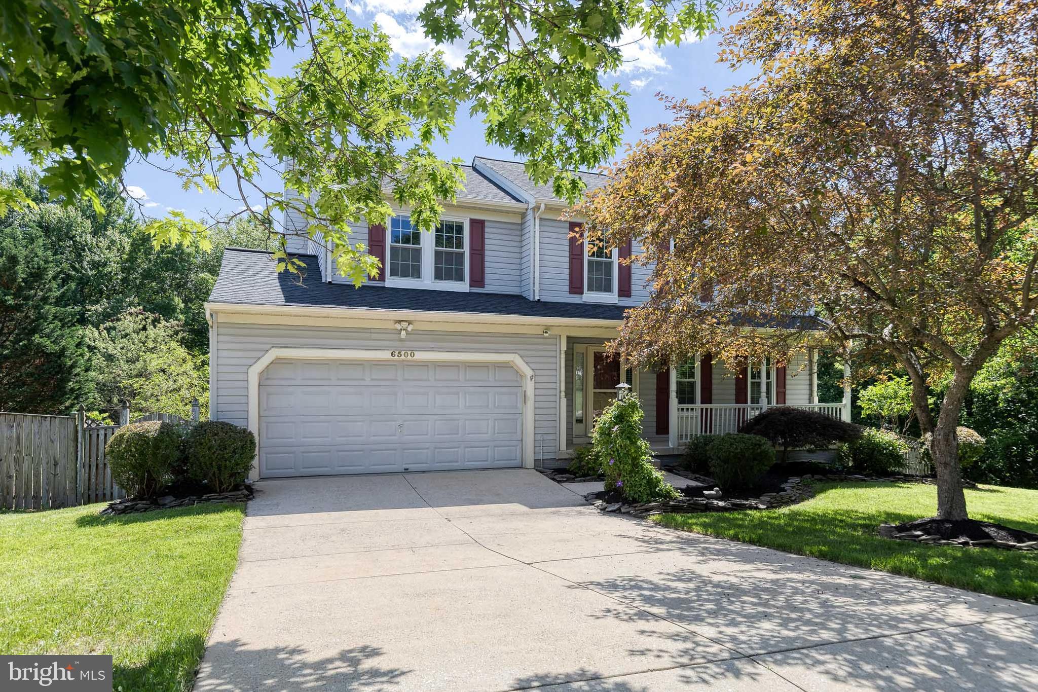 Welcome to 6500 Wesley Lane, a beautifully maintained Colonial-style home nestled beside a lush wooded backdrop, offering a rare combination of privacy, comfort, and outdoor living. From the moment you arrive, you'll appreciate the convenience of the attached two-car garage, providing easy access to the home and protection from the elements year-round. Inside, the home feels fresh and inviting, featuring newly painted interiors and brand-new carpeting on both the bedroom level and lower level.  The main floor is designed with both everyday living and entertaining in mind. Rich hardwood floors flow throughout the space, creating a warm and cohesive atmosphere. A spacious living room welcomes guests and seamlessly connects to the formal dining room, where large windows flood the home with natural light and showcase views of the surrounding greenery. The heart of the home is the well-appointed kitchen, featuring granite countertops, a custom tile backsplash, a center island with breakfast bar seating, and a dedicated area for casual dining. The open-concept layout continues into the expansive family room, where a cozy wood-burning fireplace creates the perfect gathering space for family and friends. Just off the kitchen, a screened-in deck provides a peaceful setting for morning coffee or evening relaxation while enjoying the sights and sounds of nature. The outdoor living space extends to an impressive hardscaped patio complete with a built-in fire pit, ideal for entertaining throughout the seasons. The fully fenced backyard offers both privacy and security, making it perfect for pets, play, and outdoor enjoyment.  Upstairs, the spacious primary suite serves as a private retreat, featuring ample closet space and an en-suite bathroom with a double vanity and updated luxury vinyl plank flooring. Three additional generously sized bedrooms provide comfortable accommodations for family members or guests, each offering excellent closet space and easy access to the shared hall bathroom.  The finished lower level adds even more flexibility to this exceptional home. A potential fifth bedroom or private office creates options for today's lifestyle needs, while abundant storage space helps keep everything organized. The expansive recreation room can easily serve as a playroom, home gym, media room, or additional entertaining area, making this level as versatile as it is spacious.  With its thoughtful layout, numerous updates, beautiful outdoor spaces, and tranquil wooded setting, 6500 Wesley Lane is a place you will love to call home!
