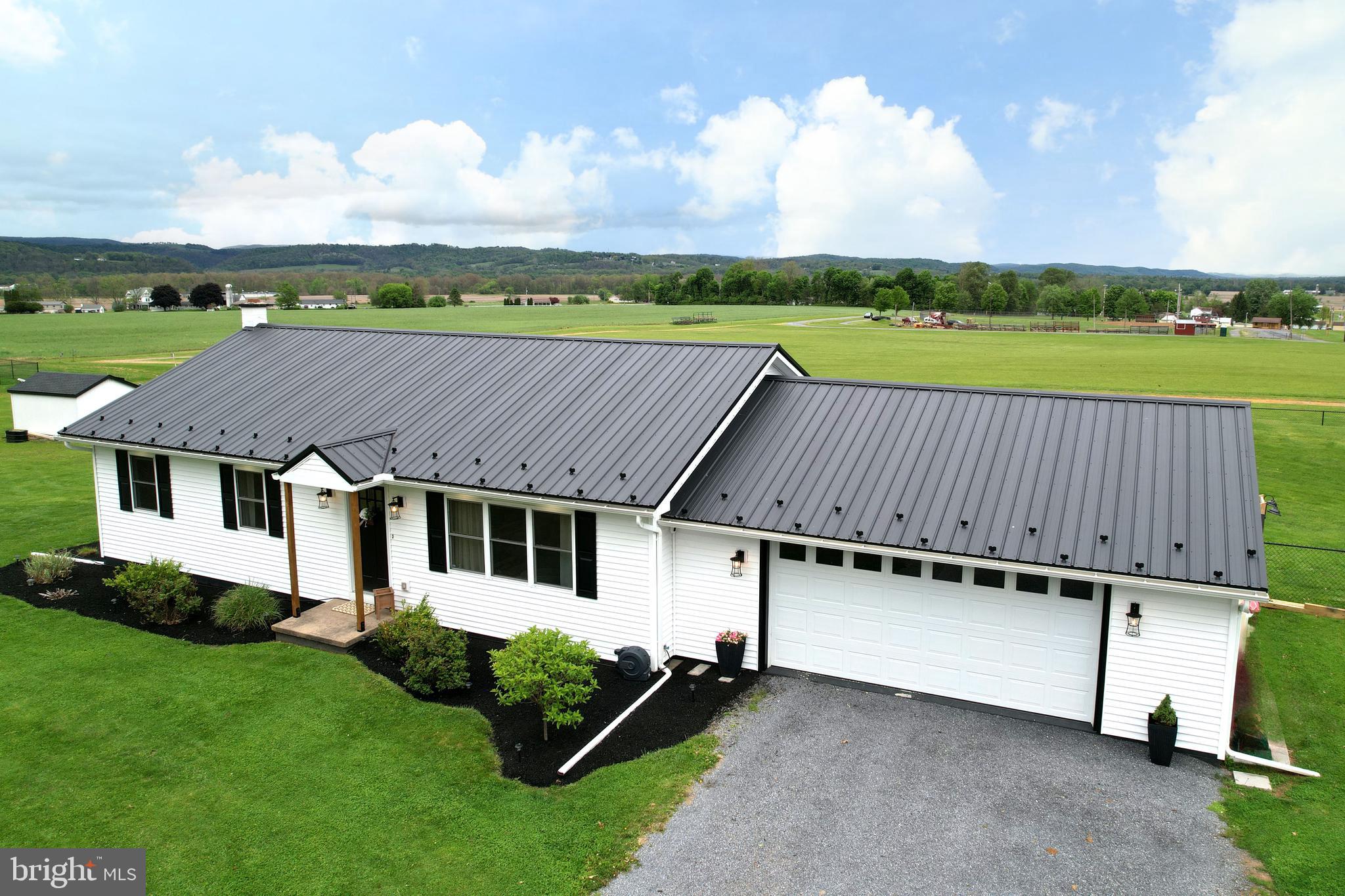 Nestled on a scenic 1-acre lot with picturesque views, this beautifully updated ranch home blends modern farmhouse style with peaceful country living. Step inside to a bright and airy open-concept layout featuring luxury vinyl plank flooring, recessed lighting, and inviting spaces designed for both everyday living and entertaining. The stunning kitchen is the heart of the home, showcasing crisp white cabinetry, a contrasting dark wood island with breakfast bar seating, elegant quartz countertops, subway tile backsplash, stainless steel appliances, farmhouse sink, and a built-in wine rack. The spacious primary suite offers comfort and privacy, while two additional bedrooms and a second full bath provide flexibility for a home office, hobby space, or additional living needs. Outside, enjoy incredible curb appeal with white siding, black shutters, a black metal roof, and an attached 2-car garage. The backyard is truly an outdoor retreat featuring an expansive covered porch with rustic wood pillars and ceiling fan, a concrete patio perfect for summer evenings, a "cowboy pool" surrounded by river rock, and even a charming chicken coop. Wide-open pasture views and picturesque mountain scenery complete this beautifully updated countryside property. *Seller is PA Licensed Real Estate Agent