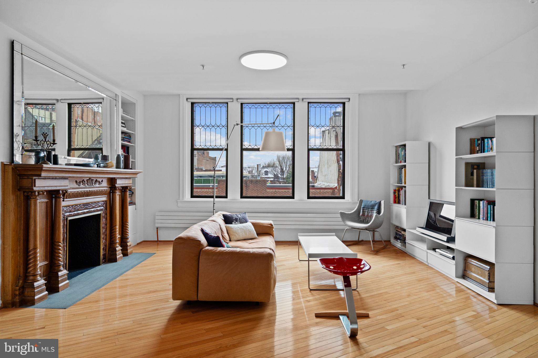 This design-forward, full-floor condominium with private elevator entrance is in a historically significant building. Truly the jewel of Washington Square West, the double-width c.1892 Italianate building with 17-inch interior masonry walls designed by noted architect Frank Miles Day was converted into a boutique condominium with just five units. The spacious, loft-inspired design in Unit 3 boasts high ceilings; frosted glass doors with pivot hinges; oak floors that run on the diagonal; and oversized windows, each of which sits above a contemporary wall-hung radiator. The understated European sensibility of the finishes leaves room for the original details to shine. In the living room, those include three south-facing leaded glass windows and a truly stunning fireplace with ornate carved mantel. The spacious dining room has its own massive original fireplace with mirrored mantel, and one of the two oversized windows has been converted to custom French doors leading to a balcony. A large kitchen with an open galley layout bridges these spaces. The 12-foot-long island with cabinets on both sides and large pantry closet provide ample storage. Crisp white Shaker-style cabinets topped with quartz and paired with white large-format stacked tile backsplash and workhorse Wolf range with Viking hood, Sub-Zero fridge, Miele dishwasher and Hansgrohe faucet create a work space that is as handsome as it is functional. The antechamber entrance to the primary suite amplifies its private nature. The spacious bedroom has a pair of oversized windows and a walk-in closet, and the equally spacious en-suite bathroom has full-wall large-format stacked ceramic tile, radiant floors, a large floating vanity with drawers, heated towel rack, and Duravit and Hansgrohe fixtures and hardware, including a trough sink and soaking tub with dual showerhead, plus Miele laundry machines. The second bedroom has two built-in bookcases and a double-width closet with mirrored doors that highlight the three striking leaded glass windows. Its en suite has the same heated floors and high-end finishes as the primary, this time with an oversized step-in shower. The gorgeous building with a Mercer tiled lobby offers the best of downtown living, with some of the city’s best dining within steps–including James Beard-nominated Vedge just a few doors down–as well as easy access to Broad St, SEPTA and PATCO for commuters, and green space at the Jefferson quad and Kahn and Seger parks.