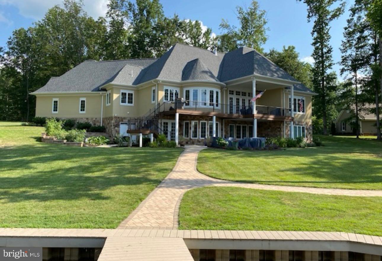 Tucked away at the end of a quiet cul-de-sac in the sought-after Noah’s Landing community, this custom-built waterfront home offers the kind of Lake Anna lifestyle people dream about. Situated on the private side of the lake, the property is designed for easy lake living with a maintenance-free bulkhead, lake-fed irrigation system, and a fantastic waterfront setup ready for long summer days on the water. Down at the shoreline, enjoy your covered boathouse featuring two slips, an electric boat lift, spacious sun deck, and storage room for all your lake toys and gear. Whether it’s boating, swimming, fishing, or simply relaxing by the water, this property is built to enjoy every season at the lake. Inside, the home offers a comfortable and functional layout with a main-level primary suite for convenience and privacy. The lower level expands the living space with three additional bedrooms, a spacious family room, and a mini kitchen—perfect for hosting guests, extended family, or creating the ideal entertaining space after a day on the water. Outdoor living is made easy with both a covered back deck and patio overlooking the peaceful waterfront setting. From quiet morning coffee to evenings spent unwinding by the lake, this home was made for soaking in the best of Lake Anna living.