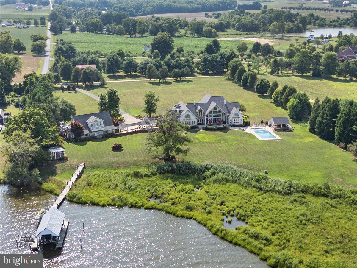 Welcome to an extraordinary estate unlike any other! This meticulously crafted home is set on a sprawling 6.48-acre lot directly along the Patuxent River. Built in 2004, this residence boasts an impressive 10,764 square feet of luxurious living space! *** Step inside to discover unparalleled custom quality. The main and upper levels level are adorned with beautiful solid Brazilian Cherry wood flooring. The main home features four elegant bedroom suites on the upper level. The primary suite, located on the main level down a private hallway, offers a serene retreat separated by French doors from the rest of the home and beautiful views of the water. A dedicated office with sizable windows provides a perfect workspace.  When you enter the formal foyer, with its two-story ceilings and marble flooring, it evokes the grandeur of historic mansions. Local artists have hand-painted the ceilings of the dining and music rooms, featuring graceful waterfowl against a blue sky.  When entering the chef's kitchen, you will notice it is equipped with high-end Sub-Zero and Wolf appliances, complemented by granite countertops and rich cherry cabinetry. Enjoy water views while cooking or dining at the kitchen table. The adjacent butler's pantry makes entertaining effortless.  The family room features two stories of Palladian windows, offering stunning views of the Patuxent River, a fireplace, an exit to the back stone deck, and an adjoining sunroom/gym with its own climate control system.*** Outside, a recently constructed pool house with an outdoor  shower, powder room, wet bar, ceiling fans, and granite countertops offers the perfect setting for high-end entertaining. The heated and cooled pool, surrounded by travertine decking and equipped with an automatic cover, ensures year-round luxury. ***The lower level provides ample space for storage or future expansion. The three -car garage with ceramic tile flooring connects via a breezeway to two separate living units. The  converted two level detached garage features 2 separate living units.*** The ground level of this additional living space features a newly renovated kitchen with cherry cabinets, a spacious bedroom with plantation shutters, two full baths, and a fully equipped laundry and pantry areas.*** The upper space includes a separate unit with a full bath, bedroom, kitchen, fireplace, and two decks overlooking the tranquil river. ***  The property also includes a pier with a covered boat slip, an uncovered boat slip, and two jet ski lifts, ideal for your watercraft.  *** From total bedroom and bath count, there  are 2 more bedrooms  and 3 additional baths in the guest apartments. There is also an additional bath in the pool house. That is a total of 7 bedrooms and 8.5 baths!  ***With an easy commute to Washington, DC, this home is a rare find in the area, offering a level of luxury and exclusivity that truly makes it a dream come true. Experience the sensation of having arrived at your own private paradise.