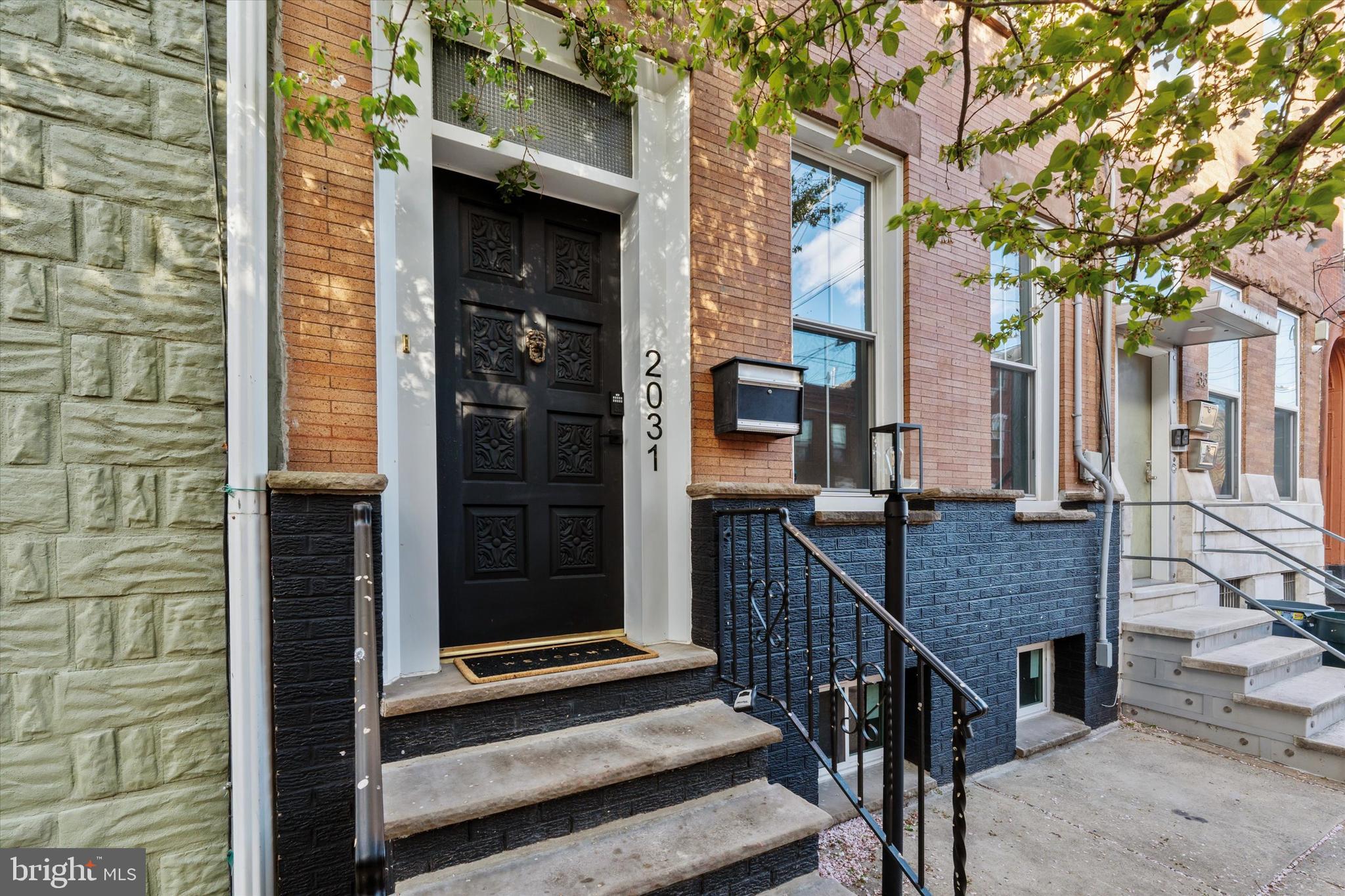 A one of a kind retreat in the city! Welcome to 2031 East Dauphin - a beautiful newly renovated and restored 5 bedroom, 2.5 bathroom home on a tree lined block in vibrant East Kensington. As you approach you'll notice the handsome ironspot brick facade and the elevated position of the home about 5ft above street level. Walk up the steps through the front door and hang your jacket or bag in the large vestibule with a scalloped glass door. Enter into the expansive great room. The property is 17 feet wide with 10 foot high ceilings, creating an incredibly spacious feel while also retaining a coziness from the character and charm of the home. The large windows allow light to flood into the home and the effect is dramatic. The original inlayed oak hardwood floors have been refinished and there are newer windows throughout the whole home. Continue back to the dining room which can accommodate a table as big as you need. Beyond, you'll find the kitchen, tastefully designed with tile backsplash, dark matte blue cabinets, brand new stainless steel appliances (range, fridge, microwave, dishwasher), and quartz countertops. Just beyond the kitchen is the laundry room/half bath with a brand new washer and dryer. Keep going and head to the big backyard, with plenty of space for a table, chairs, grill, and a bit of nature with a flowering tree and towering neighboring green pines. Back into the kitchen you'll find a back staircase where you can head upstairs to the primary bedroom with en suite bathroom. The private primary bedroom in the rear of the home is very spacious with 5 large windows that let in great natural light. Continue down the hall and notice a beautifully renovated bathroom with teal wall tile in the shower and penny tile flooring with brass fixtures. Continuing, you'll find the spacious second and third bedroom. The front bedroom boasts a charming and sizeable built-in wardrobe closet with skeleton keys original to the home. Head up to the third floor and you'll find another two large bedrooms that could also serve as work or studio spaces. There is a door to access the giant double tiered roof with a skyline view at the top, perfect for creating a roof deck. The massive basement is great for storage, creative, or flex space. In addition to the renovations throughout, other updates of note include: brand new HVAC (heat and central air), sewer line replaced, newer roof, knob and tube completely removed, new electric service cable, new windows, refinished hardwood floors and more! With so much space, original charm, and a fantastic location that's walkable to some of Philly's best restaurants, coffee shops, and bars with easily accessible public transportation to the rest of the city, you'll want to check out this truly special home.
