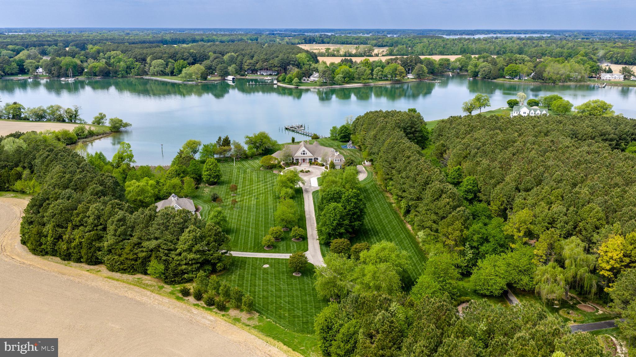 Island Creek Estate — rare total privacy, deep water dockage, meaningful architecture, and superb build quality all intersect at this remarkable, truly one-of-a-kind waterfront offering. Set on approximately 6 acres of park-like grounds with 500± feet of shoreline and 6’± MLW, the property offers exceptional water access along the peaceful expanse of Island Creek. The setting is serene and private, with a gracious approach that complements the estate’s architectural presence. Impeccably built with careful attention to detail, the residence offers 4 bedrooms and 3.5 baths within a thoughtfully designed floor plan that maximizes natural light and water views. The living room, kitchen, and dining area flow comfortably together, creating a spacious central gathering area framed by expansive windows overlooking the creek and anchored by a fireplace. The kitchen is generously sized, featuring a substantial island, quality finishes, and an inviting eat-in area suited for both everyday living and entertaining. Outdoor living is equally compelling, with a screened porch overlooking the water and an in-ground pool set against sweeping creek views. The private pier provides deep water dockage, ideal for boating enthusiasts seeking immediate access to the Chesapeake Bay watershed. A finished rec room above the attached garage offers flexible use as a media room, office, or fitness space. In addition to the attached two-car garage, the property features a substantial detached multi-bay garage equipped with a hydraulic vehicle lift, air compressor, and rough-in for a future bath — an exceptional amenity for car collectors, hobbyists, or workshop space. This exceptional Island Creek estate combines craftsmanship, privacy, and premier waterfront living in a setting that is both refined and enduring.