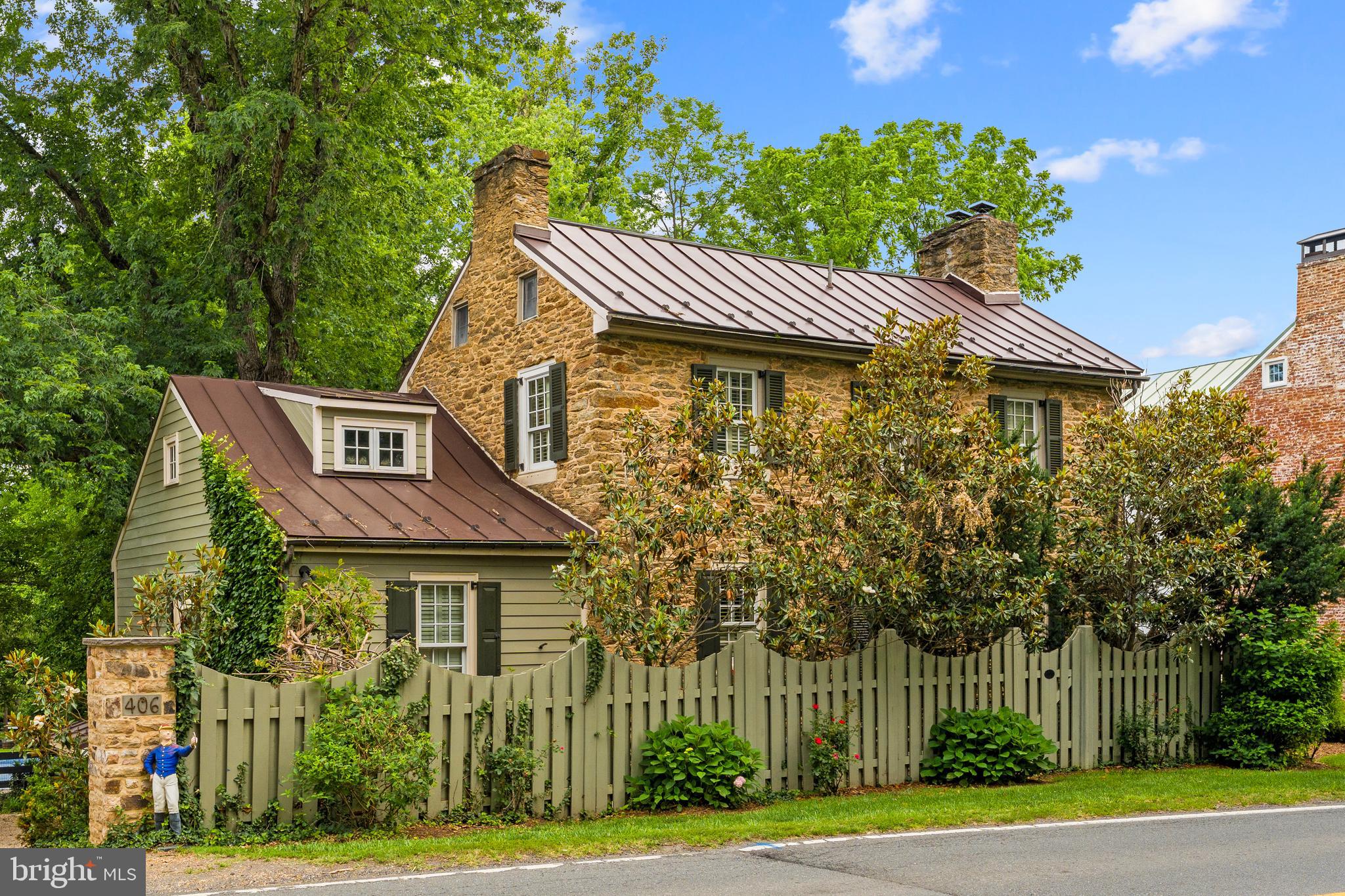 The Jacob Mann House, circa 1817 and once home to Middleburg’s local tanner, is a charming fieldstone residence ideally located on the eastern edge of the historic village. Rich in character and thoughtfully updated, the home offers three bedrooms and two full baths including a main level primary suite. Step inside to find original hardwood floors, two fireplaces, built-ins, custom cabinetry, and abundant natural light throughout. The designer kitchen features high-end appliances and looks out over a bright enclosed back porch overlooking a deck, the private gardens and a swimming pool. The finished walk-out lower level includes a spacious Tavern Room upgraded with exposed beams, custom cabinetry, a gas fireplace, and a mini-split system, along with a private office space and a Butler’s Pantry with more custom cabinetry and an exposed stone wall. Just steps from the main house, the restored Smoke House provides exceptional flexibility with a full bath, heated hardwood floors and a fireplace making it ideal as a guest suite, home office, artist’s studio or workout room. The fully fenced grounds offer rare privacy within town limits and are enhanced by mature landscaping, including more than 50 boxwoods, laurels, arborvitae, hollies, and pines. Other improvements include pool renovations, updated fencing, a tar-based pea gravel driveway, three mini-split systems, a retractable pool cover and a hot tub. Savor the privacy of a secluded in-town setting, while enjoying an easy walk to Middleburg’s shops, restaurants, library, and post office along with quick access to local wineries, breweries, and nearby walking trails through the Salamander Resort. Unique corner parcel on .48 acres fronts three streets and has subdivision potential. A rare opportunity to own a beautifully preserved historic home in Middleburg. Don't miss!