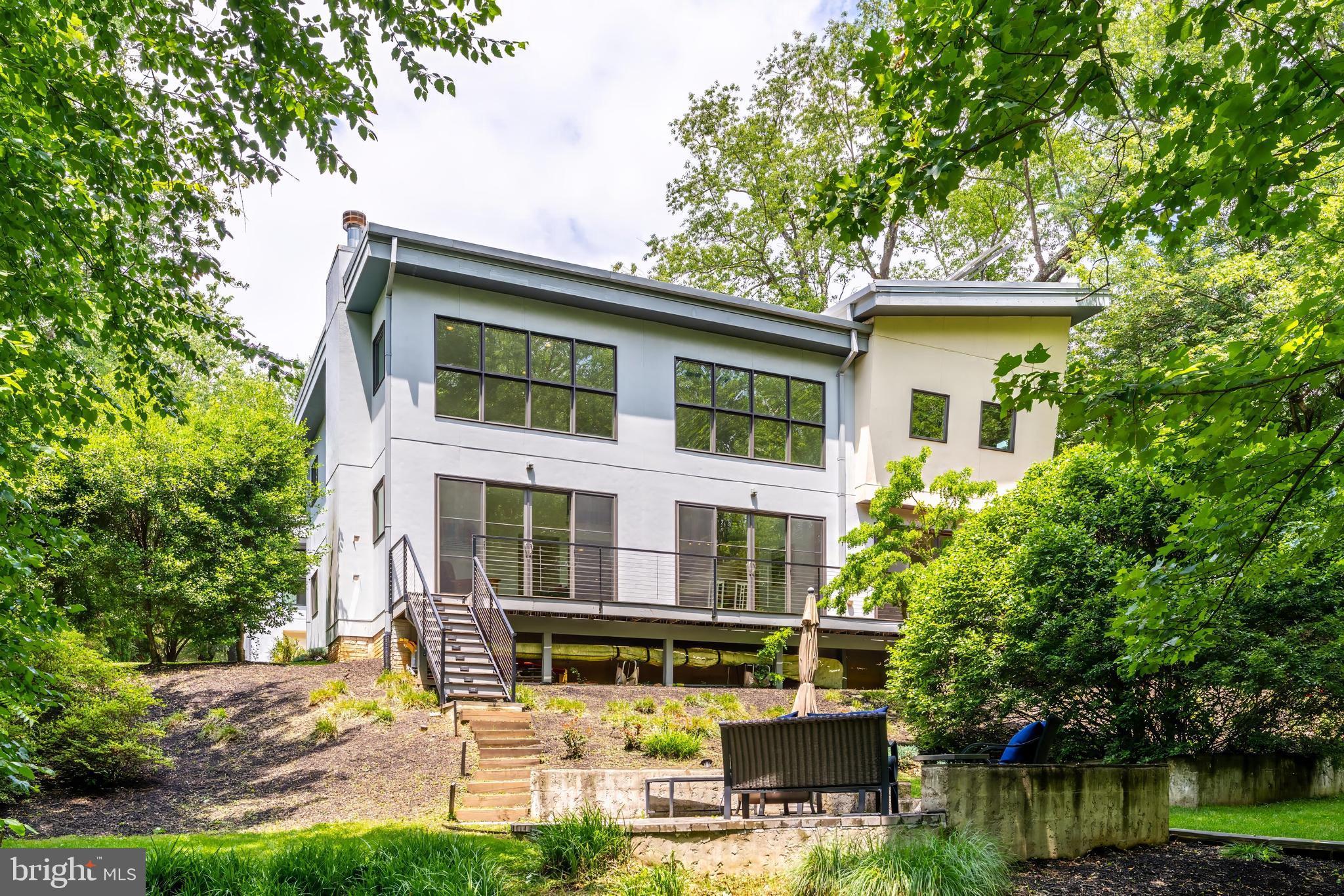 A rare opportunity to own one of Northern Virginia's most distinctive custom residences. This pioneering LEED-certified home was originally featured in The Washington Post for its groundbreaking design and environmental stewardship. This extraordinary custom build, on a gorgeous 0.47 acre lot steps from Kent Gardens ES,  was thoughtfully designed as a home that would remain relevant for decades to come. The result is a timeless architectural statement where exceptional design, sustainable innovation, and everyday livability converge.

Situated on a private, wooded lot, the home unfolds along a dramatic 85-foot visual axis. From the moment you enter, your eye is drawn through the angled gallery corridor to a breathtaking wall of glass framing uninterrupted treetop views beyond. Inspired by the unique geometry of the site, the home's striking design incorporates a subtle six-degree orientation that maximizes natural light, solar exposure, and the connection to nature.

The residence seamlessly blends a reimagined original structure with a spectacular modern addition connected by a glass enclosed bridge. This thoughtful design creates distinct yet harmonious living spaces, ideal for multi-generational living, guests, home offices, creative pursuits, or private retreats.

At the heart of the home, soaring ceilings and walls of glass define the grand living spaces. The two-story living room rises nearly 19 feet and is anchored by a wood-burning fireplace, while oversized Windsor windows and premium sliding glass doors flood the interior with natural light. Oak floors, custom millwork, designer lighting, and bespoke cabinetry elevate every space.

The chef's kitchen is a masterclass in form and function, featuring imported Pedini cabinetry, a substantial center island, custom drawer systems, Bosch double wall ovens, a Miele gas cooktop, Thermador refrigeration, appliance garage, pull-out pantry storage, and integrated ceiling speakers. Multiple rooms open directly to the expansive IPE hardwood deck, creating effortless indoor-outdoor flow for entertaining.

The upper-level primary suite serves as a private sanctuary overlooking the surrounding canopy. Vaulted ceilings, custom shades, three fully built-out closets, and a luxurious spa bath featuring a Lotti double vanity, heated floors, fully tiled walls, and a jetted soaking tub create a true retreat. An upper level home office equipped with built-in book cases and storage cabinets could also be suitable as a bedroom. 

The original front wing offers remarkable flexibility in spaces. There are two bedrooms, one with a kitchenette-equipped suite, a Jack-and-Jill bath, and abundant built-in storage. A dedicated gym/bedroom with exterior access, extensive storage areas, and a two-car garage further enhance the home's functionality.

What truly sets this residence apart, however, is its commitment to sustainable living. As one of the region's earliest LEED-certified homes, it incorporates advanced energy-efficient systems including solar thermal panels, radiant heated floors, gas backup heating, whole-house HEPA air filtration, high-performance insulation, and environmentally conscious building materials. The solar-driven radiant heating system provides an unmatched level of comfort while significantly reducing energy consumption.

Recent updates include a new HVAC system serving the front portion of the home (2024), professionally serviced mechanical systems, refinished IPE decking, and meticulous ongoing maintenance throughout.

This special home is a living expression of thoughtful design, innovation, and enduring quality. A truly one-of-a-kind offering in the heart of McLean in the sought after school pyramid of Kent Gardens ES (steps away!!), Longfellow MS and McLean HS.