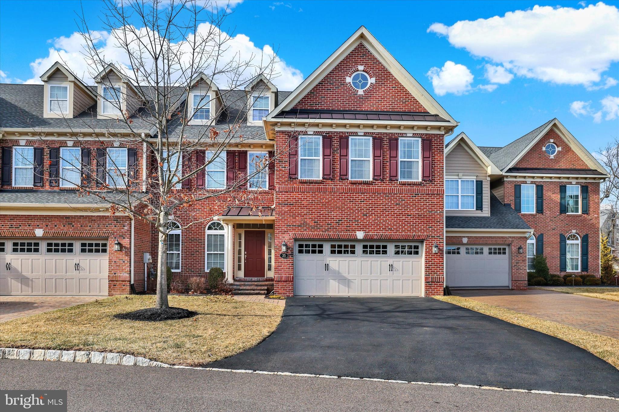 Welcome to 35 Rittenhouse Circle, located in Delancey Court, one of Bucks County’s most sought-after premier 55+ Active Adult communities. Inspired by the timeless charm of historic Philadelphia neighborhoods, the community features classic brick façades and thoughtfully designed streetscapes. This home is ideally situated on a premium lot, backing to a tranquil wooded backdrop and preserved open space, offering both privacy and natural beauty. This customized Toll Brothers–built Farnham model offers four bedrooms and three-and-a-half baths and welcomes you with a charming cobblestone walkway and covered front porch. Upon entry, a dramatic 2-story foyer sets the tone for this elegant residence. Freshly painted throughout, the home features a refined neutral and custom color palette. The formal living room is enhanced by custom crown, dentil, chair rail, and wainscoting moldings, complemented by Stanton Woodlands walnut random-plank luxury vinyl flooring, which extends throughout the entire first level. The spacious hallway leads to an open-concept design centered around the impressive chef’s kitchen. This space features upgraded granite countertops, a custom subway tile backsplash with mosaic inset, Yorktowne Maplewood cabinetry with custom pull-out shelving, under-cabinet lighting, and a large center island with seating. Additional highlights include a dual undermount stainless steel sink, Yorktowne “Java” cabinetry, and custom millwork. High-end stainless steel appliances include a Jenn-Air six-burner cooktop with custom vented hood, convection wall oven and microwave, Bosch dishwasher, KitchenAid wine refrigerator, and Samsung French-door refrigerator. A generous walk-in pantry and adjacent breakfast area provide additional convenience and functionality. Step through the triple-pane sliding glass doors to an expansive, fenced EP Henry patio, framed by brick privacy walls and overlooking a serene wooded backdrop and open green space—ideal for outdoor relaxation or entertaining. The formal dining room, located adjacent to the kitchen, features a tray ceiling, custom moldings, an upgraded chandelier, and wall sconces. The dramatic two-story family room offers a wall of windows with custom treatments, a gas Heatilator fireplace with glass enclosure, quartz surround, custom mantle, built-in speakers, recessed lighting, and an upscale ceiling fan, perfect for both everyday living and entertaining. Completing the main level is a hallway leading to the mudroom, powder room, mechanical room, and direct access to the two-car garage. A turned staircase with solid wood treads, custom railing, and metal balusters leads to the second level, which features engineered hardwood flooring throughout. This level includes a spacious loft overlooking the family room. The luxurious owner’s suite boasts a tray ceiling with crown molding inset, elegant window treatments, and two walk-in closets with custom organizers. The spa-inspired owner’s bath features a dual vanity with custom cabinetry, an expansive dual-head shower with seamless glass enclosure and custom tilework, and a Kohler Archer® air-jetted whirlpool tub with heated bubble massage hydrotherapy. Additional features include ceramic tile flooring, recessed lighting, and a private commode. Two additional well-appointed bedrooms, a hall bath with tub/shower, and a full laundry room complete the second level. A glass door leads to the finished 3rd level, offering a 4th bedroom, a large recreation area, random-plank hardwood flooring, a walk-in closet, two additional storage closets, and a dedicated mechanical room for the 2nd HVAC system. A custom full bath with tub/shower and random-plank marble flooring completes this level. Additional amenities include a 3-zone HVAC system, Andersen windows, a security system, and numerous high-end upgrades throughout. Every detail of this exceptional home has been thoughtfully designed for refined livinging!