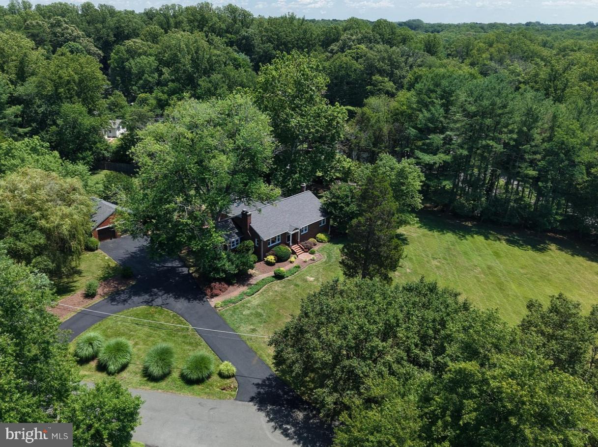 Set on a 2-acre homesite, 6251 Woodfair Drive presents a rare combination of privacy, space, and natural beauty. Mature trees and pastoral lawns create a picturesque setting and peaceful backdrop year-round, while the generous distance from neighboring homes delivers an estate-like feel. The expansive lot provides endless opportunities for outdoor entertaining, recreation, gardening, or simply enjoying the tranquility of nature. Located in the established Fairfax Station community, this property combines the privacy and serenity you seek with convenient access to shopping, dining, parks, and commuter routes. Inside, the solid hardwoods, classic built-ins and brick hearth fireplaces PLUS the renovated white kitchen & great room create an inviting modern interior while maintaining the home's original charm. The stunning  great room addition under a soaring cathedral ceiling with four skylights floods with natural light for an exceptional gathering area for everyday living and entertaining.  Step out to the wrap-around sun deck and the eye-popping back yard that stretches wide and deep! Two outbuildings: small one with electricity/carpet suited for possible she-shed? The larger one set deep on the lot helps stow equipment, etc. Back inside, main level includes a primary suite with private bath, two additional bedrooms, and a full hall bath. Be sure to notice the quaint "yesteryear" laundry chute and built-in hall storage. The finished lower level features new LVP flooring, a huge recreation room, finished bonus room, additional den/potential bedroom, and a full bath—adding the flexible living space much appreciated today. Well maintained throughout with major updates: 2024 roof + four skylights with solar blinds, 2022 kitchen remodel (+ 2026 dishwasher), and a 2022 mini-split system serving the great room + more!