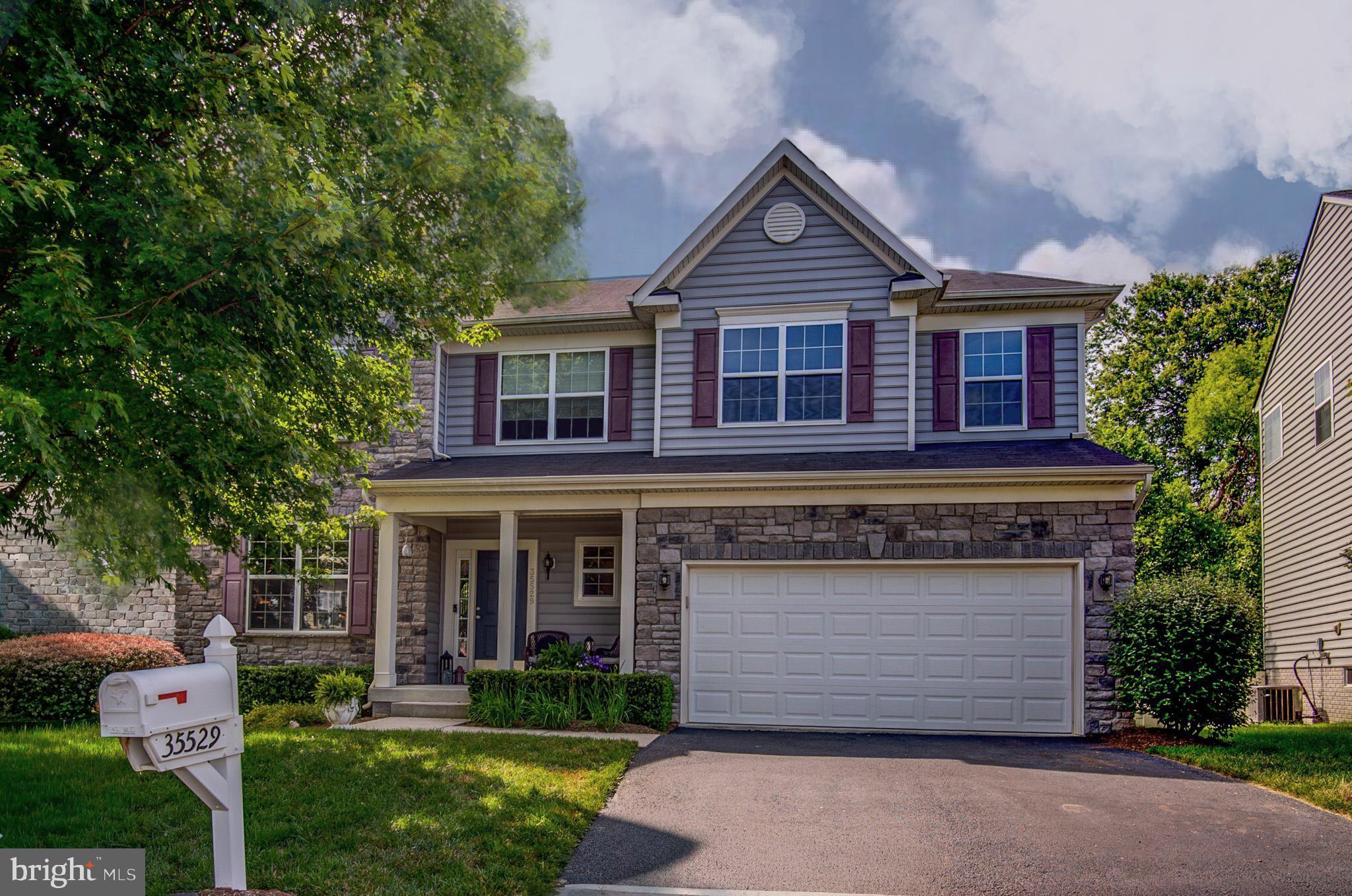 If a beautiful homesite is high on your wish list, 35529 Hudson Street deserves your attention. Nestled on a picturesque lot with mature trees and a seasonal stream, this property offers a setting that is increasingly difficult to find. And that's before you step inside the pristine stone-front Colonial that complements it perfectly. From the charming covered front porch overlooking mature landscaping accented by boxwoods, a stately oak tree, and a graceful Japanese maple to the expansive Trex deck overlooking the wooded backyard, this home embraces its natural surroundings at every turn. A dramatic two-story foyer with hardwood flooring welcomes you inside and opens to an elegant living room with crown molding and a gracious dining room ideal for entertaining. Large windows frame views of the treed rear yard, bringing the outdoors in. At the rear of the home, the open-concept kitchen and family room create a comfortable space for everyday living and gatherings alike. The kitchen features black granite countertops, a striking Moroccan marble backsplash, 42-inch cabinetry, abundant prep space, a center island with seating, pendant lighting, recessed lighting, and a sink positioned to enjoy backyard views. Step outside to the incredible Trex deck, designed with two generous gathering areas overlooking mature trees and the seasonal creek below. During parts of the year, the gentle sound of flowing water creates a peaceful backdrop for outdoor dining, entertaining, or simply relaxing. White railings accented by black pickets add a sophisticated finishing touch to this outdoor retreat. The family room is anchored by a stunning stacked-stone fireplace with stone mantel and filled with natural light from multiple rear-facing windows. The seamless connection between the kitchen, family room, and deck makes entertaining effortless. The main level also offers a large coat closet, secondary pantry, powder room with a window, and access to the oversized two-car garage. A notable feature of this home is its advanced fresh-air management system utilizing a Heat Recovery Ventilator (HRV) or Energy Recovery Ventilator (ERV). This system continuously replaces stale indoor air with filtered fresh outdoor air while mechanical dampers regulate oxygen intake. The result is enhanced indoor air quality and exceptional energy efficiency, helping the home remain comfortable year-round. Upstairs, four generously sized bedrooms each feature a walk-in closet. The primary suite offers abundant natural light, two oversized walk-in closets, a spacious sitting room, and a luxurious bath with raised dual vanities, a large shower, and an oversized linen closet. The sitting room is the perfect nook for reading, enjoying a morning coffee, practicing yoga, or simply appreciating the luxury of extra space. The suite comfortably accommodates a king-sized bed and additional furnishings while still feeling open and inviting. Three additional bedrooms offer excellent closet space and flexibility, while the hall bath features a raised vanity and tub/shower combination. Completing the upper level is a highly sought-after walk-in laundry room with built-in shelving and storage. The unfinished walk-up lower level features abundant natural light, double sliding glass doors to the backyard, only four steps to grade, and a three-piece rough-in for a future bath. Whether you envision a recreation room, guest suite, fitness area, home office, media room, or additional living space, the possibilities are endless. Mountain Valley residents enjoy an exceptional small-town lifestyle just minutes from the heart of Round Hill. Local favorites include Tammy's Diner, charming antique shops, a veterinary clinic, and convenient neighborhood markets for everyday essentials. Round Hill Park hosts holiday celebrations, seasonal festivals, and family-friendly events throughout the year, while the Round Hill Aquatic Center offers swimming, fitness, and recreation opportunities for all ages.