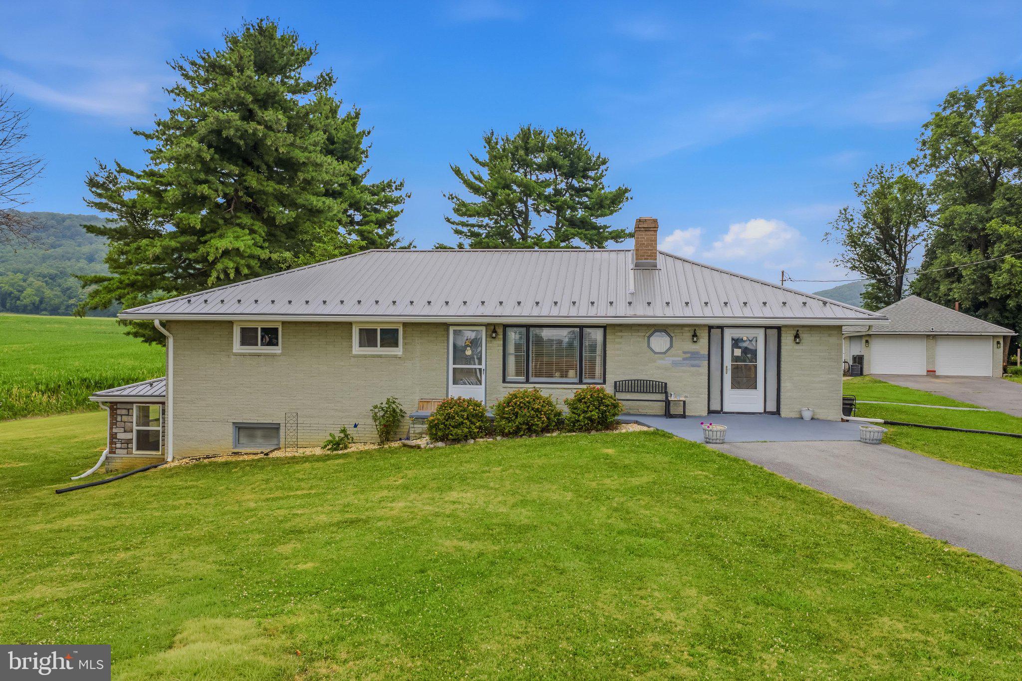 Welcome to this spacious and well-built 4-bedroom, 2.5-bath brick and stone rancher, ideally situated on two lots totaling 0.52 acres in the charming town of Clear Spring, MD.  Offering over 3,026 square feet of living space, this solidly constructed home features a durable metal roof and a layout designed for comfortable everyday living.

Enter through the convenient mudroom into the heart of the home, where the kitchen boasts gas cooking and an adjoining dining area perfect for family meals and entertaining. The inviting living room provides ample space to gather, while the generously sized primary bedroom features its own fireplace and private half bath. Three additional bedrooms have original hardwood floors.

The full unfinished basement offers endless possibilities for expansion or storage and includes a second fireplace, half bath, laundry area with utility sink, utility room, and access to an enclosed porch overlooking the side yard.

Outside, enjoy relaxing in the sunroom complete with a full awning for shade and a heated floor for comfort.  The partially fenced backyard opens to breathtaking panoramic countryside views, creating the perfect setting to unwind. A detached two-car garage with large side windows and an expansive asphalt driveway accommodating four or more vehicles provide exceptional parking and workspace.

This home has much potential to be your dream home and is ready for your personal touches.  Conveniently located as the first home coming into town—or the last one leaving—you'll enjoy the perfect combination of small-town charm, scenic surroundings, and easy access to nearby amenities. This unique property offers space, quality construction, and incredible views that are ready to be enjoyed.  Schedule your viewing today!