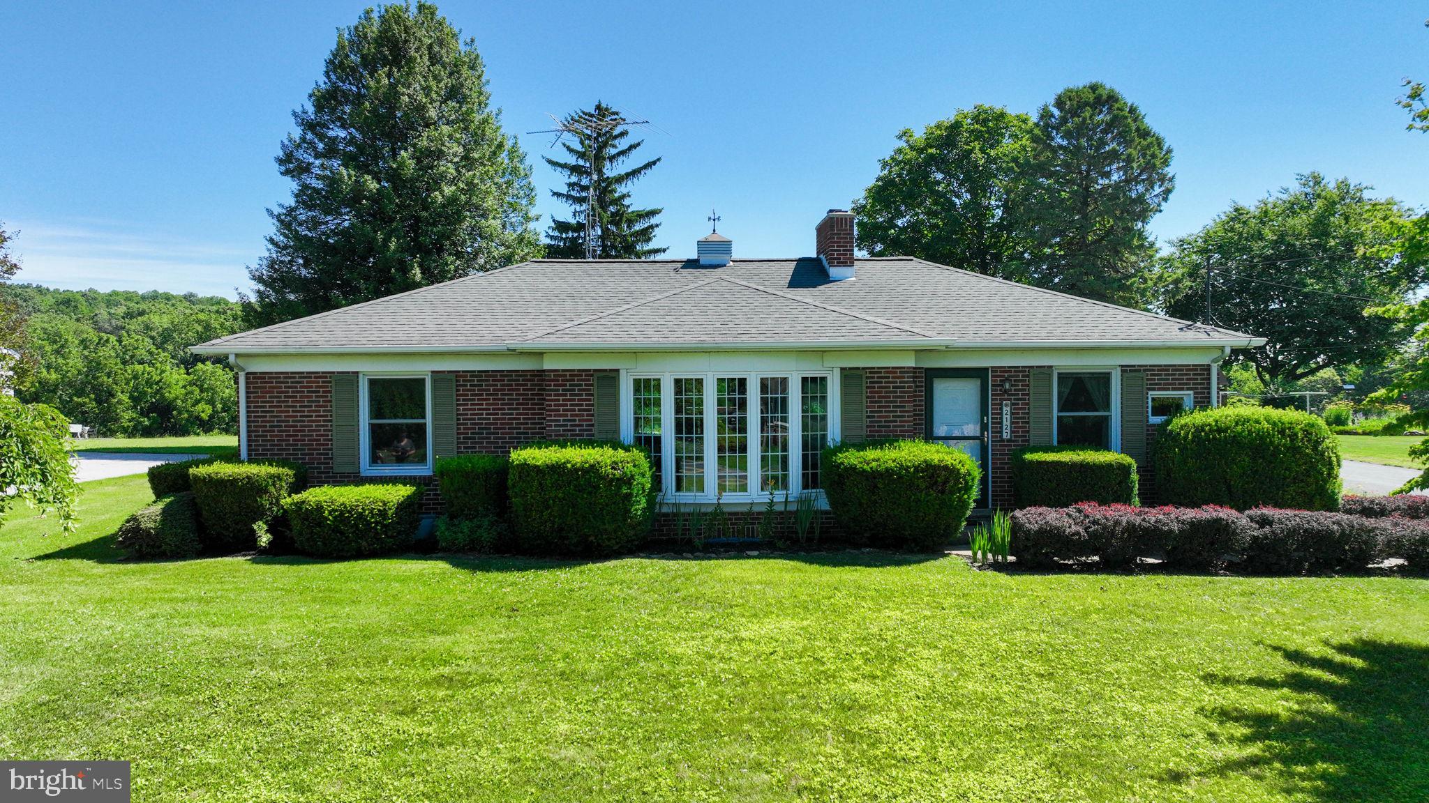 Over 3,000 square feet of finished living space with potential secondary living quarters and breathtaking countryside views! Backing to open green space and surrounded by mature shade trees, beautiful landscaping, garden areas, and a charming courtyard, this property offers a peaceful setting with exceptional flexibility.

The main level features a bright and open layout highlighted by an expansive sunroom that overlooks the scenic surroundings and provides access to the covered patio. The kitchen is centrally located between the living room and dining room, creating a functional flow for everyday living and entertaining. Two generously sized bedrooms feature recently uncovered hardwood flooring, while the full bath includes dual vanity areas and a walk-in shower.

The finished lower level is ideal for extended family, guests, or multi-generational living with its spacious recreation room, bar area, second kitchen, utility room, and walk-in shower. This versatile space provides excellent potential for secondary living quarters while still offering plenty of room for entertaining and recreation.

Enjoy the beauty of the outdoors from every angle with mature trees, established landscaping, garden areas, and picturesque views of the surrounding countryside.