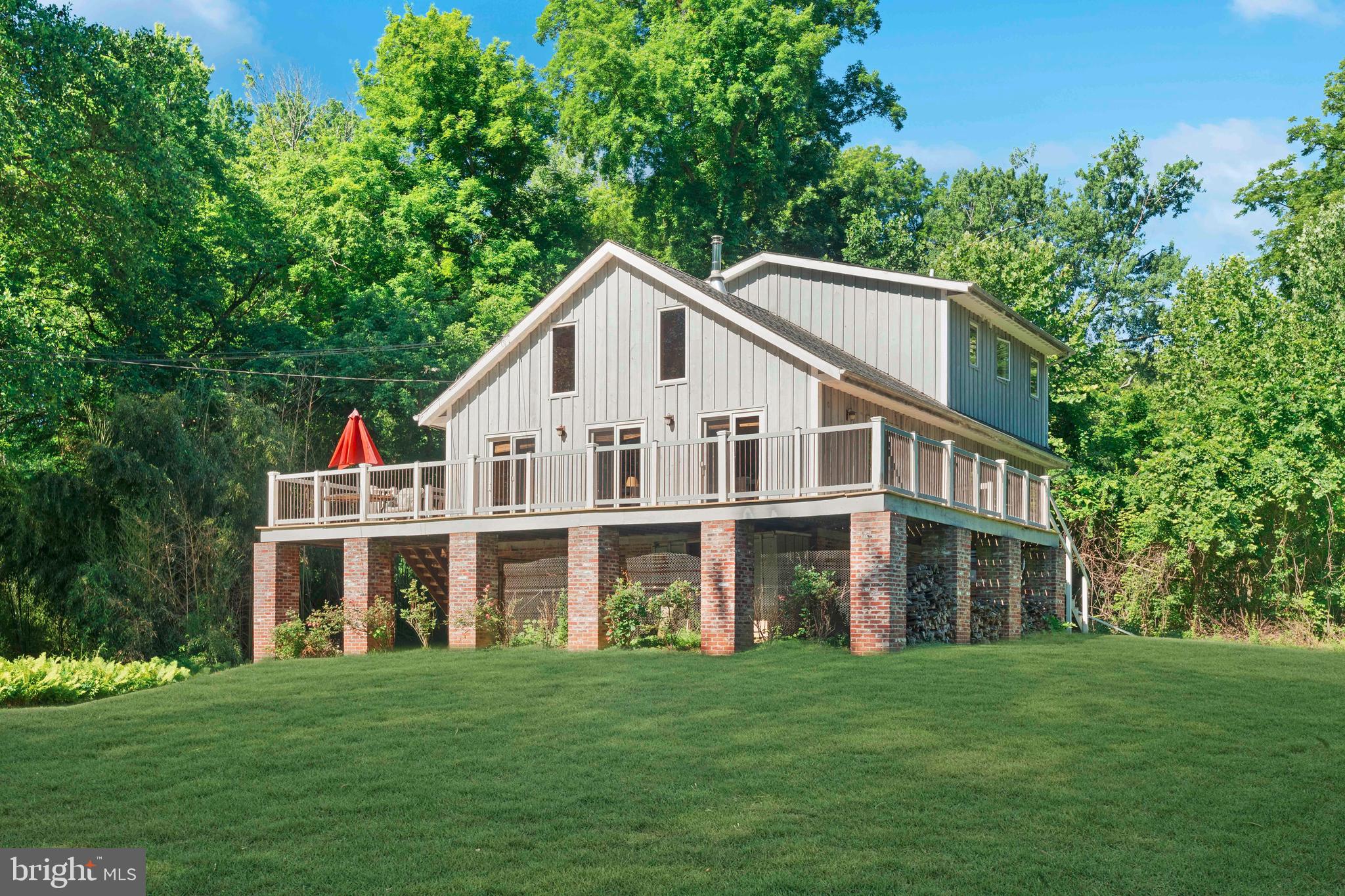 Tucked away on more than two acres of private riverfront property, this extraordinary custom built contemporary home offers a rare opportunity to enjoy the beauty of nature without sacrificing comfort or craftsmanship. Surrounded by mature trees, abundant wildlife, and breathtaking river views, this one of a kind retreat feels worlds away from it all while still providing the conveniences of modern living.

Thoughtfully designed and elevated with an elevation certificate, the home showcases stunning red oak post and beam construction, soaring vaulted ceilings, and beautiful wide plank yellow pine flooring that create warmth, character, and an impressive sense of space. Natural light pours into the open concept living areas, highlighting the home's architectural details and connection to the surrounding landscape.

The heart of the home is the inviting great room, where a wood burning stove serves as a striking focal point and creates the perfect setting for cozy evenings. Just beyond, expansive windows and access to the wraparound deck frame picturesque views of the river and natural surroundings, offering an ideal space for entertaining, outdoor dining, or simply relaxing while taking in the peaceful scenery.

The kitchen combines rustic charm with everyday functionality, featuring granite countertops, hickory cabinetry, a stainless steel sink, and ample workspace for cooking and gathering. The main level also includes two spacious bedrooms and a full bathroom with ceramic tile flooring.

Overlooking the great room below, the second floor loft provides a versatile space for a home office, reading nook, or additional living area. The private primary suite offers a tranquil escape, complete with a well appointed bathroom featuring a cherry vanity, soaking tub with shower, and a separate shower stall.

The lower level offers exceptional flexibility with an oversized two car garage and an impressive 29 by 21 workshop. A gas line is already available, providing the opportunity to add heat if desired and further customize the space to suit your needs.

One of the property's most remarkable features is its river frontage and riparian rights. The land extends across the road to the river itself, allowing you to enjoy direct access to your own private stretch of waterfront. Spend your days fishing, relaxing by the water, watching wildlife, or simply enjoying the tranquility of your own natural sanctuary.

Additional features include a whole house generator for added peace of mind and the rare combination of privacy, acreage, and waterfront ownership.
