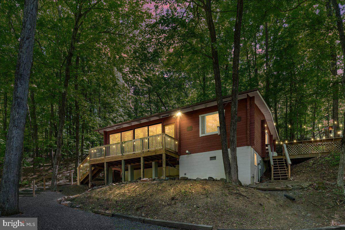Tucked into a peaceful wooded setting less than one mile from Bryce Resort, this 3-bedroom, 1.5-bath retreat offers the perfect escape midway between Front Royal and Harrisonburg. Ideal as a vacation getaway, full-time retreat, or investment property with short-term rentals allowed, the home is designed for relaxation and year-round enjoyment. Inside, warm wood-lined walls and ceilings create a cozy mountain-lodge atmosphere, while large windows and skylights fill the home with natural light and serene views of the surrounding woods. A wood stove adds comfort on chilly evenings, and the private sauna offers the perfect place to unwind after a day outdoors. Multiple decks and a fire pit provide inviting spaces to enjoy the peaceful natural surroundings. Recent updates include a new roof in 2022, water heater replaced in 2023, and new washer and dryer installed in 2023. The detached two-car garage offers additional storage for outdoor gear and equipment and sits on a separate lot that is included in the purchase. Outdoor recreation abounds in every season with skiing, snowboarding, ice skating, and snow tubing at nearby Bryce Resort during the winter months, and PGA championship golf, mountain biking, hiking, and summer fun at Lake Laura the rest of the year. A local farmers market held Wednesday mornings is located less than a mile away, adding to the appeal and convenience of this inviting mountain retreat.