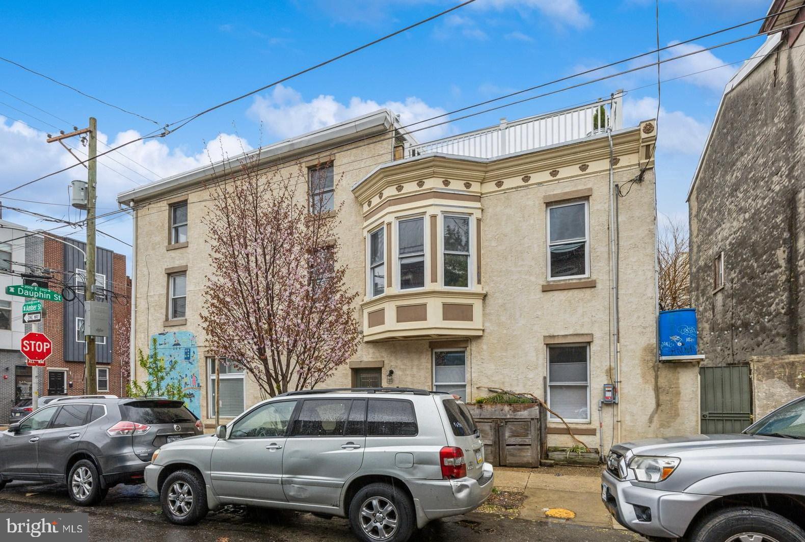 Here's something very rare:  A large 3-story, 5+ Bedroom corner building with huge storefront type studio space (still legal for Commercial) on the 1st Floor, including a full bath. This is two blocks off Frankford Ave with great window light, and so many unique extras. 1ST FLOOR: Enter from the front on Dauphin or side  entrance on Amber Street : 1ST FLOOR FRONT is a large studio space with exposed timbers, spot lighting, large picture windows and a stylish full custom tiled bath. 1ST FLOOR MIDDLE is large area for dining or extra living space, open into a contemporary full kitchen with stainless steel appliances, 5 burner gas cooking and plenty of cabinet space. 1ST FLOOR REAR exits to outside patio, very private, with room for plants, grilling and company.  2ND FLOOR: Large front bedroom with closet and incredible natural light on 2 sides (this is a corner property). Middle Bedroom - with window to Amber Street and Rear Bedroom with  large bay-window, fan and incredible light. 2ND FLOOR REAR: Large full bath with clawfoot tub, custom tile and glass shower, and double vanities.  Adjacent to bath is laundry alcove with large capacity washer/dryer. 3RD FLOOR: Front Bedroom with corner windows,  and another bedroom/den area featuring walkout door to rooftop space for relaxing. BASEMENT is very large with plenty of space for storage, craft, music, and features Bilco type loading doors from the sidewalk for easy load-in/load-out.  House has a long list of electrical, plumbing, and heating upgrades adding value to an already special find.  This is steps away from Frankford Avenue where Fishtown & East Kensington have continued non-stop investment over the last two decades.  The Market Frankford El Train is 3 blocks down on Dauphin St for a 10 minute trip to Center City. Interstate 95 is close for direct access to Bucks County, New Jersey, PHL Airport and Delaware.  House is a pleasure to walkthrough and easy to show. --Thanks---