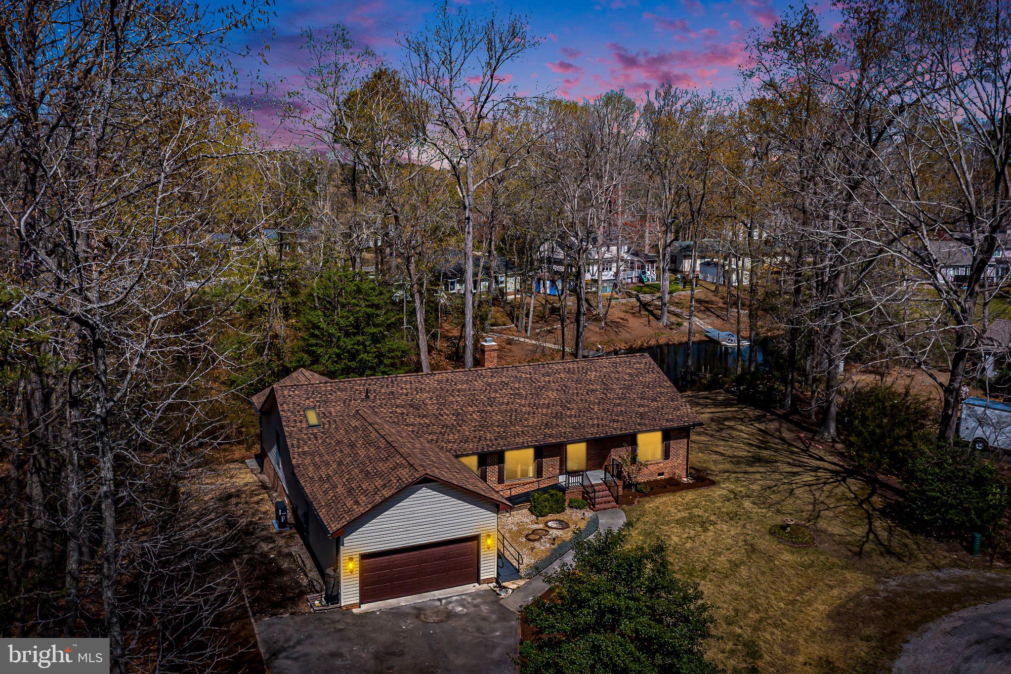 Welcome to your own lakefront retreat tucked away in the heart of Essex County, where small-town charm meets waterfront living at its finest. This stunning brick home offers an impressive 2,384 square feet of thoughtfully designed living space with three bedrooms and two bathrooms that blend comfort with timeless elegance. Step through the inviting entry into a formal living room that sets the tone for effortless entertaining. The dining room flows seamlessly into a spacious family room anchored by a cozy gas log fireplace, perfect for those cozy evenings . Vaulted ceilings add a sense of grandeur throughout, while beautiful wood floors provide warmth and character.  The updated kitchen is a culinary dream, featuring sleek stainless-steel appliances and gorgeous granite countertops. The expansive primary suite serves as a true sanctuary, complete with a zero entry luxurious tiled shower and a soaking tub.  Step outside and discover the real magic. A private pier on the lake shore, offering endless opportunities for fishing, kayaking, or simply soaking in views. The property also boasts a paved driveway, an attached two-car garage, a brand-new roof installed in 2025, and a new heat pump, Handicap Ramp, garage lift & an encapsulated Crawl Space. Lakefront homes like this rarely come to market in such pristine condition.