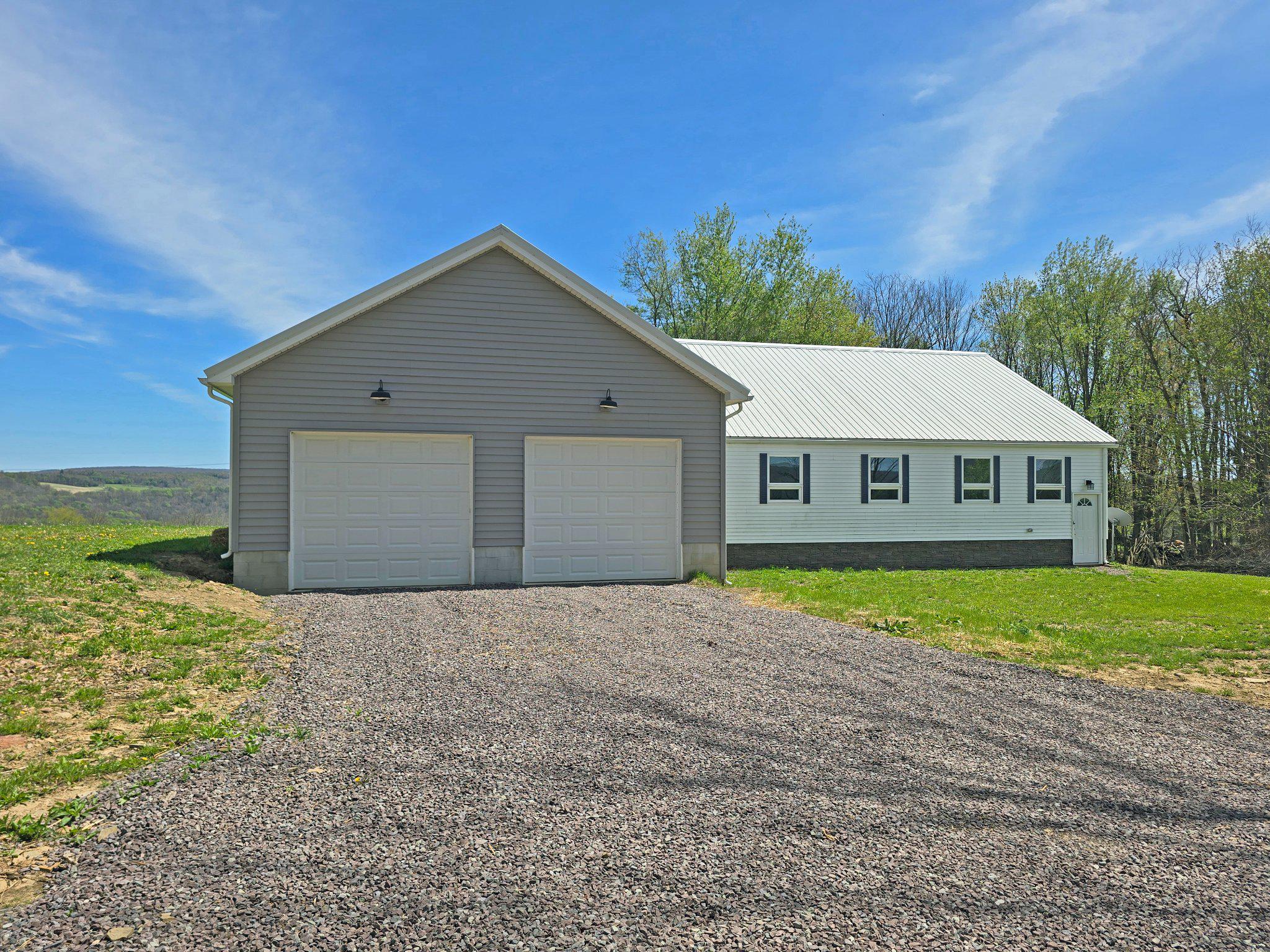 Built and designed for easy one-level living, this well-maintained 2 bedroom, 2 bath home sits on a picturesque 1 acre lot with scenic country views and plenty of potential. The bright, open floor plan features abundant natural light, a spacious family room, and a fully equipped kitchen with beautiful oak cabinetry, solid surface countertops, and room for a table or island. A convenient stacked washer and dryer are located on the main level for added ease. The finished upper-level bonus room offers flexible space for a home office, study, guest area, or additional living space. Enclosed front and back entryways provide excellent mudroom options or cozy spots to relax and take in the surrounding countryside. The full unfinished basement includes an additional washer and dryer, with plenty of room for ample storage. Outside, enjoy the low-maintenance metal roof and vinyl siding on both the home and attached 2-car garage. A ramp provides easy access to the main level, enhancing convenience and accessibility. The spacious yard is a blank canvas—ready for gardens, outdoor entertaining, recreation, or your own custom landscaping vision. Move-in ready and thoughtfully designed, this property offers comfort, practicality, and peaceful country living.