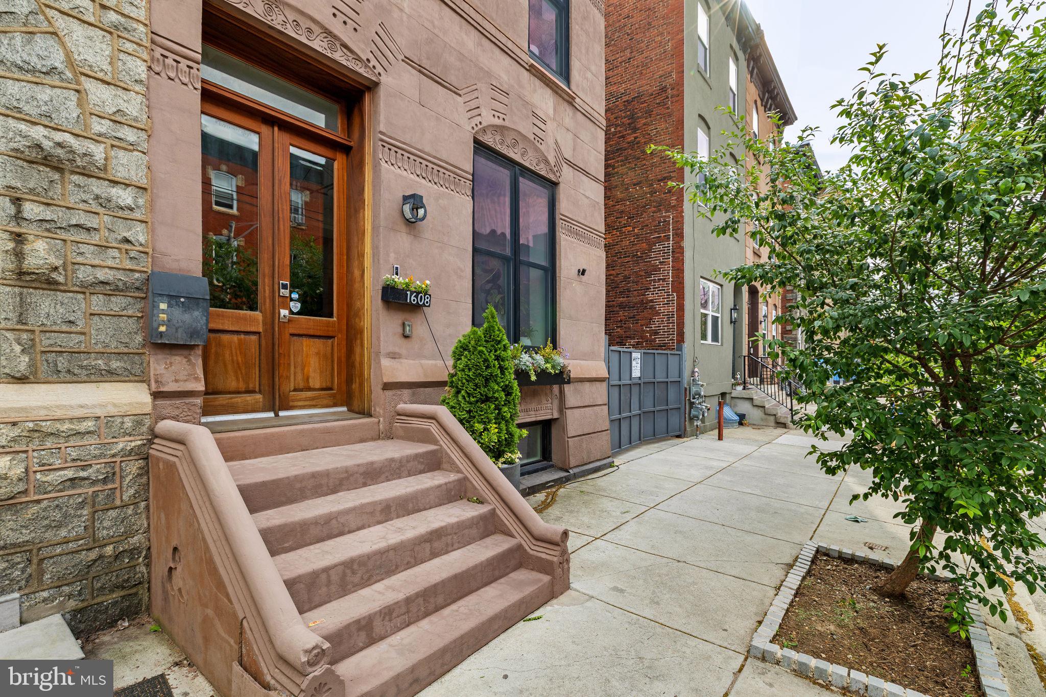 Set on an expansive 30+ foot-wide lot along one of Graduate Hospital’s most sought-after blocks, 1608 Christian Street is a striking brownstone that blends architectural presence with modern livability—anchored by seamless indoor-outdoor flow and the everyday ease of attached two-car parking.

From the moment you enter, the scale is undeniable. Soaring  12-foot ceilings on the main level and oversized proportions create an airy, gallery-like quality rarely found in city living. The layout unfolds with intention across multiple levels, designed to support both daily life and elevated entertaining.

The main level is both polished and practical. A generous living room with a gas fireplace flows into a defined dining area and a beautifully appointed kitchen featuring an oversized island with seating for six, high-end appliances (Wolf, SubZero), custom cabinetry, and stone countertops. Just beyond, a large terrace extends the living space outdoors—ideal for morning coffee, casual dinners, or hosting with ease. A powder room and a thoughtfully designed mudroom with direct access to the terrace and parking complete this level.

The second floor opens into a spacious family room—an inviting, flexible setting for movie nights or quiet retreat. The adjacent primary suite is expansive, with a custom-outfitted walk-in closet and a spa-like bath featuring marble floors, a double vanity, a freestanding soaking tub, and an oversized glass-enclosed shower with dual showerheads. The bedroom is filled with natural light from south- and west-facing windows and offers space for a sitting area or office.

The third level includes two generously sized bedrooms and bathrooms, along with a well-appointed laundry room and a hall kitchenette complete with a beverage refrigerator, sink, and dishwasher—an elevated convenience rarely found.

Floating stairs lead to the roof deck, complete with an outdoor kitchen and sweeping skyline views—designed for entertaining at every level, from intimate evenings to larger gatherings.

A finished lower level with a powder room further expands the home’s versatility, ideal for a media room, fitness space, or guest overflow.

Throughout, the home is fully integrated with smart technology, including automatic bedroom blinds, a security system with electronic entry, app-controlled lighting and thermostats, and a Sonos sound system with multiple zones and surround sound in the main living area.

Positioned within the historic Black Doctors’ Row, the home is part of a culturally significant corridor that once housed a remarkable concentration of Black physicians and professionals—adding a meaningful layer of legacy to an already exceptional address. Originally the rectory to the former First Baptist African Church, 1608 Christian has been thoughtfully reimagined by the design team that transformed the neighboring historic church into The Deacon, a luxury event space & hospitality venue.

Just beyond your door, the best of the city is within reach—Rittenhouse Square, Italian Market, Queen Village, and Passyunk Square are all within a 15-minute walk—along with neighborhood cafés, restaurants, and daily conveniences. Nearby grocery options, including GIANT Heirloom Market, Sprouts Farmers Market, and Target, round out the neighborhood experience.

Two years remaining on the 10-Year Tax Abatement.