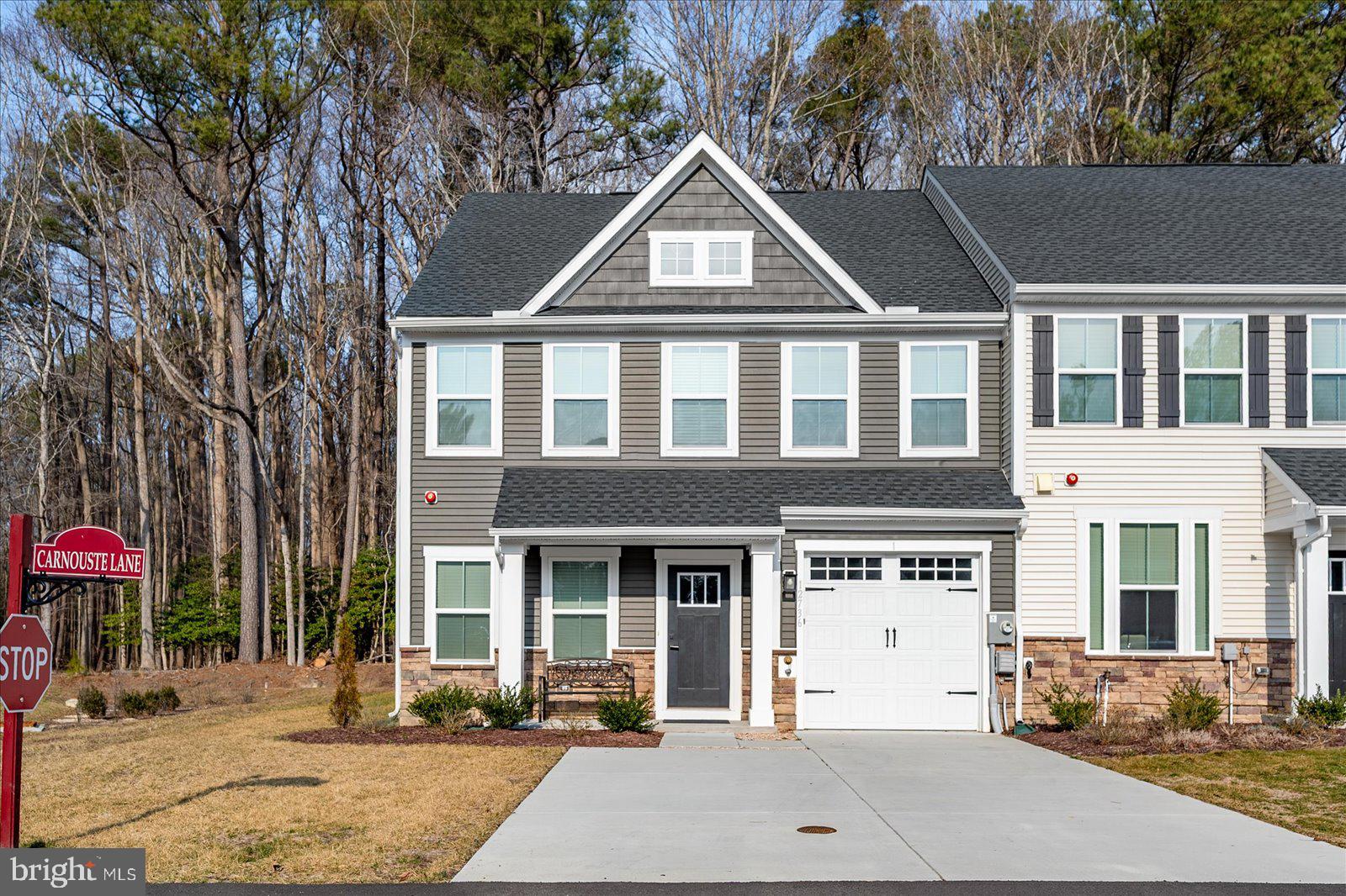 Elegant end-unit townhome in the prestigious golf course community of River Run, Built in 2024, this 3-bedroom, 2.5-bath residence offers privacy and serenity with a paver patio and backyard backing to a tranquil wooded setting. The thoughtfully designed main level features an open-concept living area highlighted by a gourmet kitchen with quartz countertops, center island, stainless steel appliances, gas range, pendant lighting, and crown molding. The adjoining great room, and sunroom create a seamless space ideal for both everyday living and entertaining. The first-floor primary suite offers a tray ceiling, spacious walk-in closet, and a luxurious en-suite bath with dual vanities and a frameless glass shower. A dining room, laundry room and powder room complete the main level, with durable luxury vinyl plank flooring throughout. The upper level includes two additional bedrooms, each with walk-in closets, a full hall bath, a versatile loft overlooking the great room, and a utility/storage room. Additional highlights include an insulated one-car garage, concrete driveway for extra parking, shake siding, irrigation system, and numerous designer upgrades throughout. River Run residents enjoy resort-style amenities including an 18-hole Gary Player designed golf course, pro shop, on-site upscale restaurant, outdoor pool, tennis courts, community marina, fitness center, and lawn maintenance is included in the HOA. Ideally located close to Ocean Pines, West Ocean City, Ocean City, shopping, dining, and entertainment—this exceptional townhome offers luxury living in a premier coastal community.
