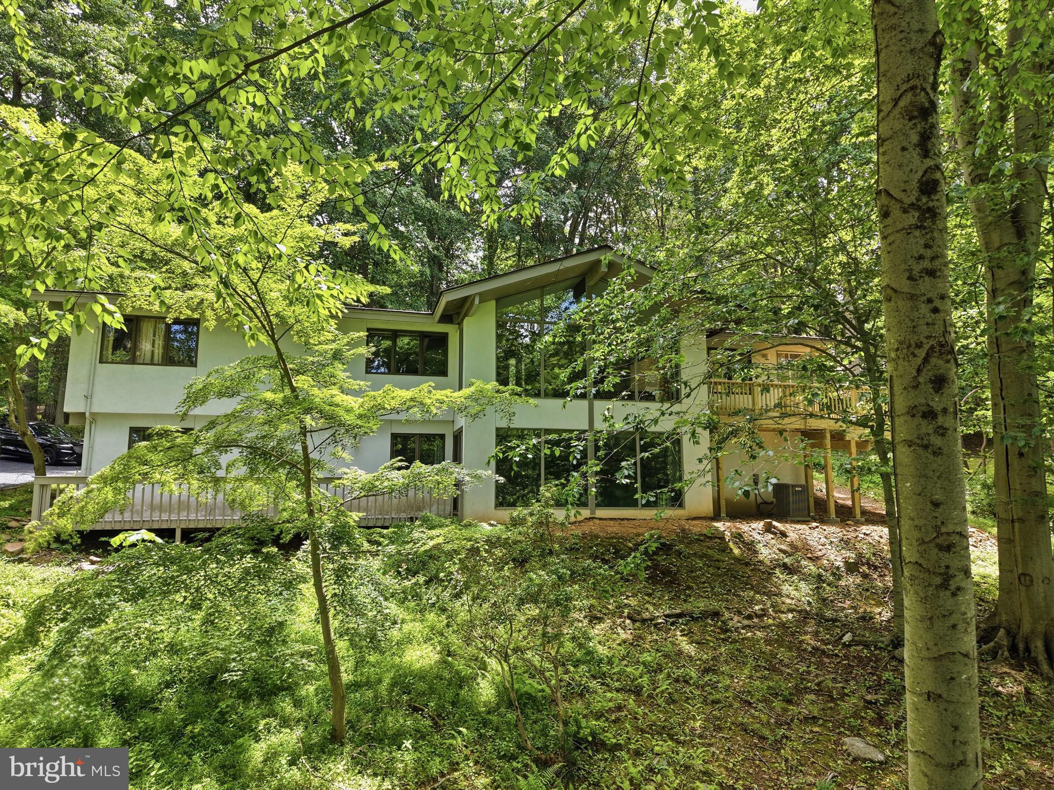 This stunning McElroy-designed residence offers five bedrooms, three full baths, and one half bath, seamlessly blending mid-century modern architecture with the tranquility of a private woodland setting in the sought-after Greene Countrie section of Newtown Township. Perched atop a hillside, this exceptional home feels like a year-round retreat, featuring soaring ceilings, exposed beams, an open-concept floor plan, and dramatic floor-to-ceiling windows that flood the interior with natural light and frame breathtaking views of the surrounding woods from nearly every room. Designed for effortless indoor-outdoor living, the home opens to a brand-new oversized deck, perfect for relaxing, dining, and entertaining while immersed in nature. The lower level offers a spacious family room, three additional bedrooms, two full baths, a laundry room, and ample storage. Extensive recent updates include a new roof, new sliding glass doors throughout, new lower-level flooring, newly refinished hardwood floors on the main level, four beautifully renovated baths, a new garage door, a brand-new deck, and new kitchen appliances. Combining architectural significance, modern updates, and a serene natural setting, this remarkable property is ideally located with easy access to shopping, dining, and amenities in Wayne, Newtown Square, and Bryn Mawr, as well as convenient access to I-476.