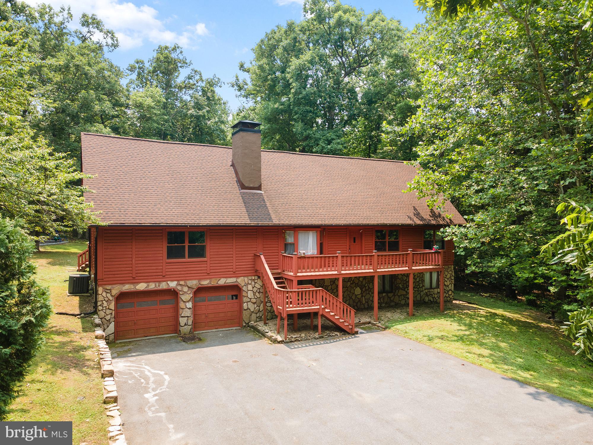 OPEN HOUSES - Saturday (7/25) and Sunday (7/26) from 12-2PM!! Backing directly to Patapsco State Park and down a private road, this custom 5BR/3BA log home on 3 private acres is the ultimate woodland retreat you've been waiting for.  Define your every day by having unfettered access to nature and explore over 16,000 acres out your back door - what an experience! The spacious yet cozy home with over 3,000sf features wood beam ceilings throughout and stunning cathedral-beamed ceilings upstairs along with many other custom rustic and design touches throughout. The first floor features a large walk-up deck spanning the front of the home. The entryway features the fantastic exposed staircase and bright bay window open to the eating area with stone fireplace and wood stove. The kitchen features all newer appliances, ample cabinetry, the washer/dryer, and glass doors leading out to the back deck. The large 24x24 family room has another set of doors to the back deck for amazing indoor/outdoor flow, log walls, lots of windows, and plenty of room for multiple seating areas and large gatherings. Also on the main level is the primary suite with a slider to the back deck, full en suite bath with walk-in shower, and closets. There are two other bedrooms and full bath with tub/shower combo on the main floor, all with stunning views. Upstairs, find a truly expansive bedroom, game room, family room, or whatever you need - with amazing soaring ceilings, closets, potential for a second story deck, and true-to-the-home hardwoods spanning the amazing space. There is so much potential here! There is another vaulted, beamed bedroom upstairs and a third full bath with tub/shower combo. This property combines rustic feel with everything you'd want in a home, and there is so much potential to transform spaces to fit your lifestyle and add updates that elevate the property even more. There is a full unfinished basement, and decks spanning both the front and rear of the property. The chirping birds and sounds of nature will become part of your everyday rhythm. Recent improvements include a new roof (2021), well pump and water filtration system (2022), newer kitchen appliances (2023), and pellet stove (2023). Enjoy the feel of living away from it all in the woods with no neighbors in sight, but in the amazingly convenient and desirable location Marriottsville offers. Experience a setting that simply can't be recreated in a one of a kind custom retreat waiting for you to call it home.