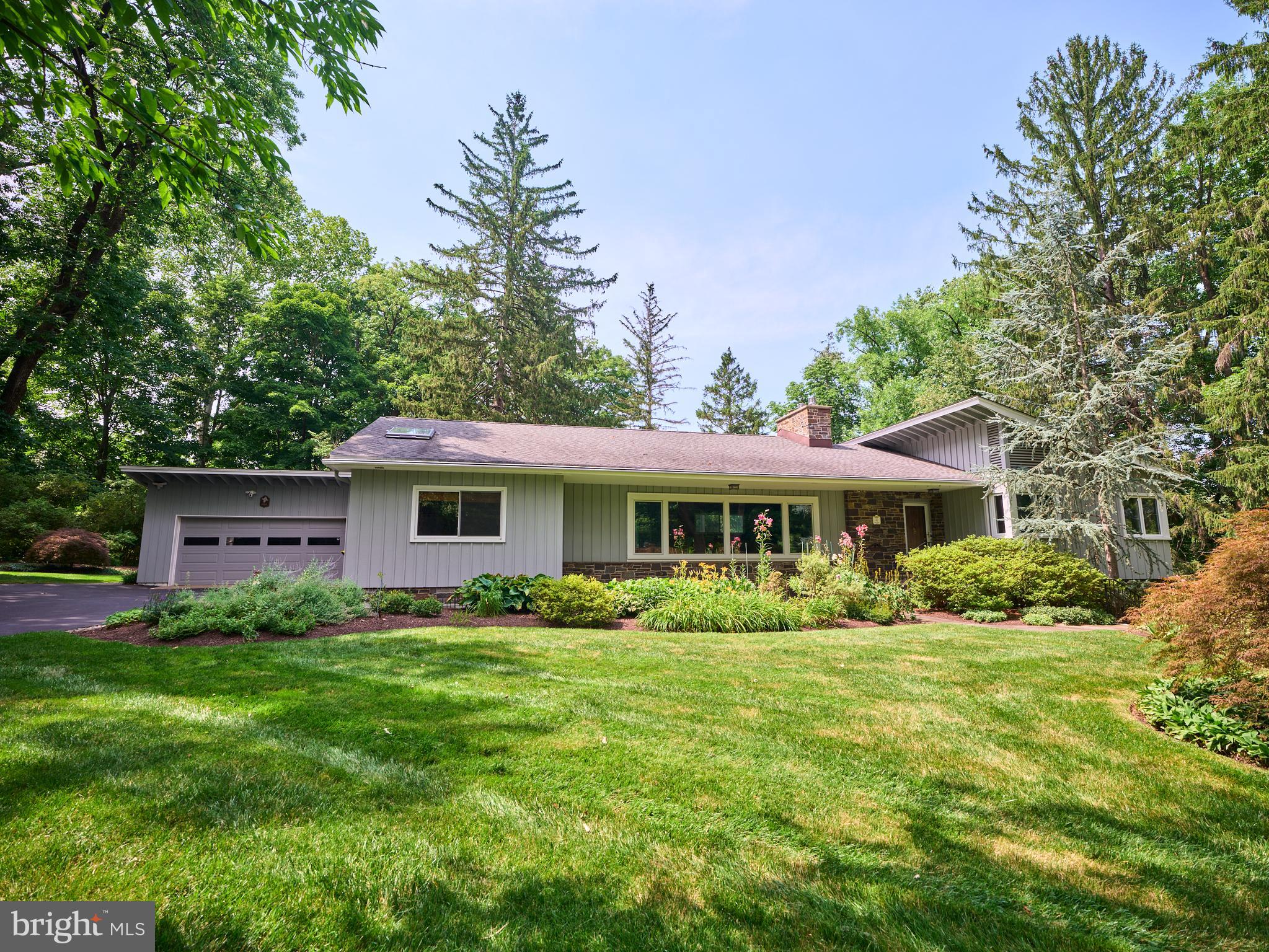 Nestled along one of Solebury Township's most coveted country lanes, this beautifully maintained ranch home is set back in a peaceful, bucolic setting surrounded by mature landscaping, vibrant gardens, and a lush, private yard. Offering approximately 2,000 square feet of comfortable one-level living, the home also features a spacious, partially finished walk-out lower level that opens to the rear and side yards.
A welcoming foyer leads to two generously sized bedrooms and a full hall bath with a tub/shower combination. Beyond, the home opens into a bright, open-concept living area where the living room, dining room, and kitchen flow seamlessly together. The living room is anchored by a gas fireplace, while the well-appointed kitchen features granite countertops, JennAir double ovens, a Bosch induction cooktop, and a Bosch dishwasher. Sliding doors from the dining area open to a large deck overlooking the picturesque backyard—perfect for outdoor dining, entertaining, or simply relaxing. A cozy sunroom also enjoys tranquil views of the gardens and rear yard. Privately situated just off the kitchen, the primary suite includes a beautifully renovated bath with granite countertops, a double vanity, a freestanding soaking tub, and a glass-enclosed shower. Additional highlights of the main level include wood floors and wood-paneled walls, abundant natural light from large windows, access to a walk-up attic, and an oversized two-car garage.
The walk-out lower level significantly expands the living space with an impressive 33' x 23' family/recreation room featuring a second gas fireplace and direct access to a charming side patio. An additional finished 20' x 10' room adjacent to the utility area is ideal for a game room, home office, fitness space, or hobby room. The utility room includes the washer and dryer and provides access to two large crawl spaces offering exceptional storage.mRecent improvements include a newer HVAC system, newer hot water heater and a recently serviced generator for added peace of mind. Ideally located just minutes from the heart of New Hope Borough and across the river from Lambertville, New Jersey and down the hill to a park and access to the canal toe-path for hiking, biking and nature watching. This exceptional property offers convenient access to acclaimed restaurants, boutique shopping, galleries, and outdoor recreation, all while enjoying the privacy, beauty, and tranquility of one of Solebury Township's most desirable settings.