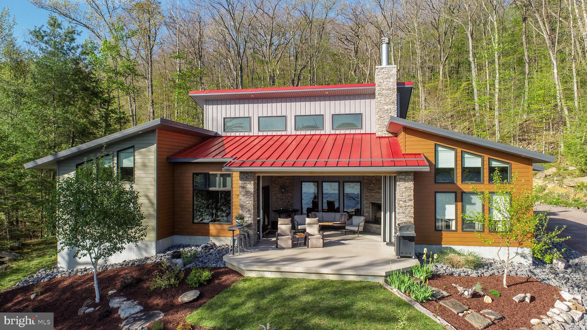 Experience elevated lake living within this iconic, contemporary retreat boasting 228 feet of pristine Deep Creek Lake frontage, a Type A dock, and 1.5 private acres. Featuring three spacious ensuite bedrooms and thoughtfully curated custom finishes throughout, this exceptional home showcases poplar ceilings, wormy chestnut trim, custom birch doors, maple kitchen cabinetry, and a striking walnut kitchen countertop, which anchors the gourmet kitchen. A dramatic NanaWall system seamlessly opens the stunning three-season room with a stacked stone wood-burning fireplace to an expansive lakeside patio showcasing breathtaking western sunset views over the water. Gather around the lakefront firepit for evening s'mores and endless stories. Geothermal radiant heat delivers both efficiency and luxury during the winter months, while a standing seam metal roof and steel siding create a durable, fortress-like mountain retreat built to last. Additional highlights include an oversized heated, two-car garage with abundant space for all your lake and mountain gear, a whole-house generator for added peace of mind during Deep Creek’s winter storms, and an ideal location just minutes from WISP Resort, marinas, restaurants, and area attractions. Call now for more details or to schedule your private showing at this one-of-a-kind Deep Creek Lake masterpiece!
