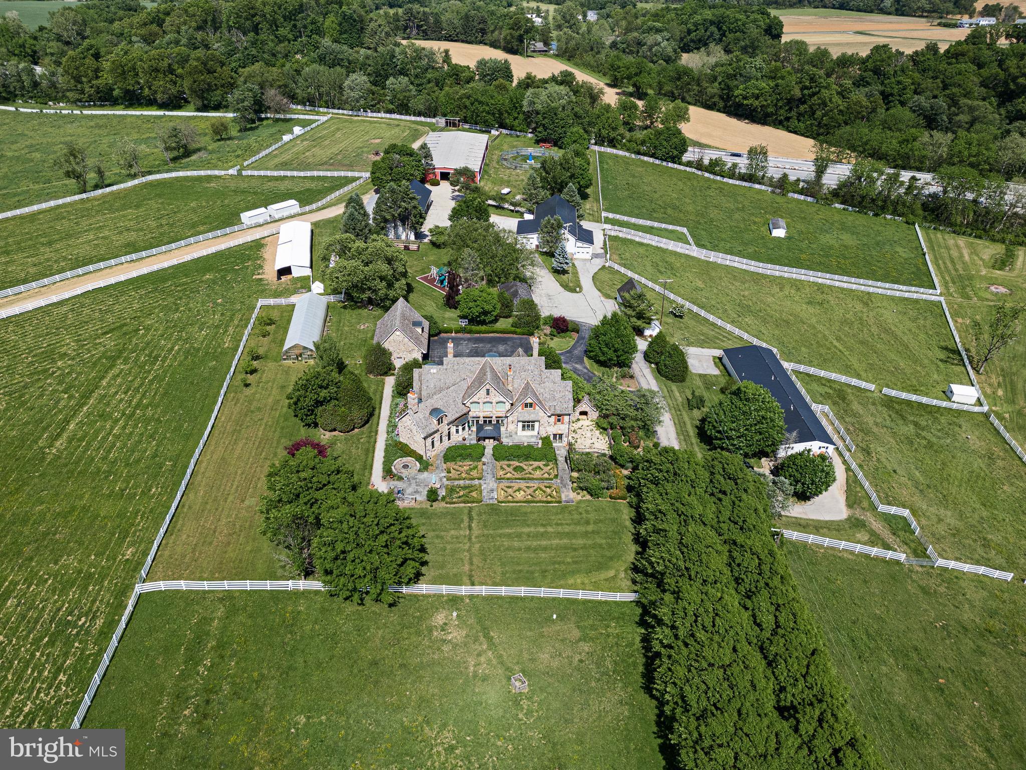 If you’ve been dreaming of wide-open space, privacy, and a true countryside lifestyle, this extraordinary equestrian estate delivers on every level. Set on over 67 breathtaking acres of rolling hills just minutes from the Maryland border, the property offers a rare combination of beauty, functionality, and relaxed luxury living. A gated entrance leads to a long, tree-lined drive, winding through picturesque paddocks and setting the tone for what’s to come. At the heart of the property is a stunning custom-built stone home, designed for both everyday comfort and effortless entertaining. Inside, you’ll find 5 bedrooms, 4 full baths, and 3 half baths, along with warm, thoughtfully designed spaces throughout. The grand foyer makes an immediate impression, opening to a formal dining room and a richly detailed study complete with custom built-ins, a fireplace, and its own wet bar—creating the perfect work-from-home retreat. The expansive great room is filled with natural light, anchored by a soaring fireplace and walls of windows that frame sweeping views of the gardens and surrounding countryside. From there, the home flows seamlessly into the chef’s kitchen, complete with a Wolf range, double Sub-Zero refrigeration, a large island, and inviting spaces for gathering. Upstairs, a library-style hallway connects four spacious bedrooms, along with flexible office space and convenient second-floor laundry. The walk-out lower level is designed for relaxing and having fun, featuring a lounge and billiards area with a double-sided fireplace, a private theater, fitness room, full kitchen, guest suite, and even a dedicated dog wash. Outside, the property truly shines. Whether you're an equestrian professional or simply want room to roam, the farm is incredibly well-equipped with 61 stalls across multiple barns, 21 paddocks, indoor and outdoor arenas, and plenty of open space. A gazebo with an announcer’s booth adds a unique touch for those who want to host events, while the chicken coop, greenhouse, and mix of tillable land, pasture, and woods add both charm and versatility. With additional features like a detached six-car garage and a flexible tenant residence, this is a property that offers endless possibilities—whether you're looking to run a working farm, create a private retreat, or simply enjoy the peaceful beauty of country living every day.