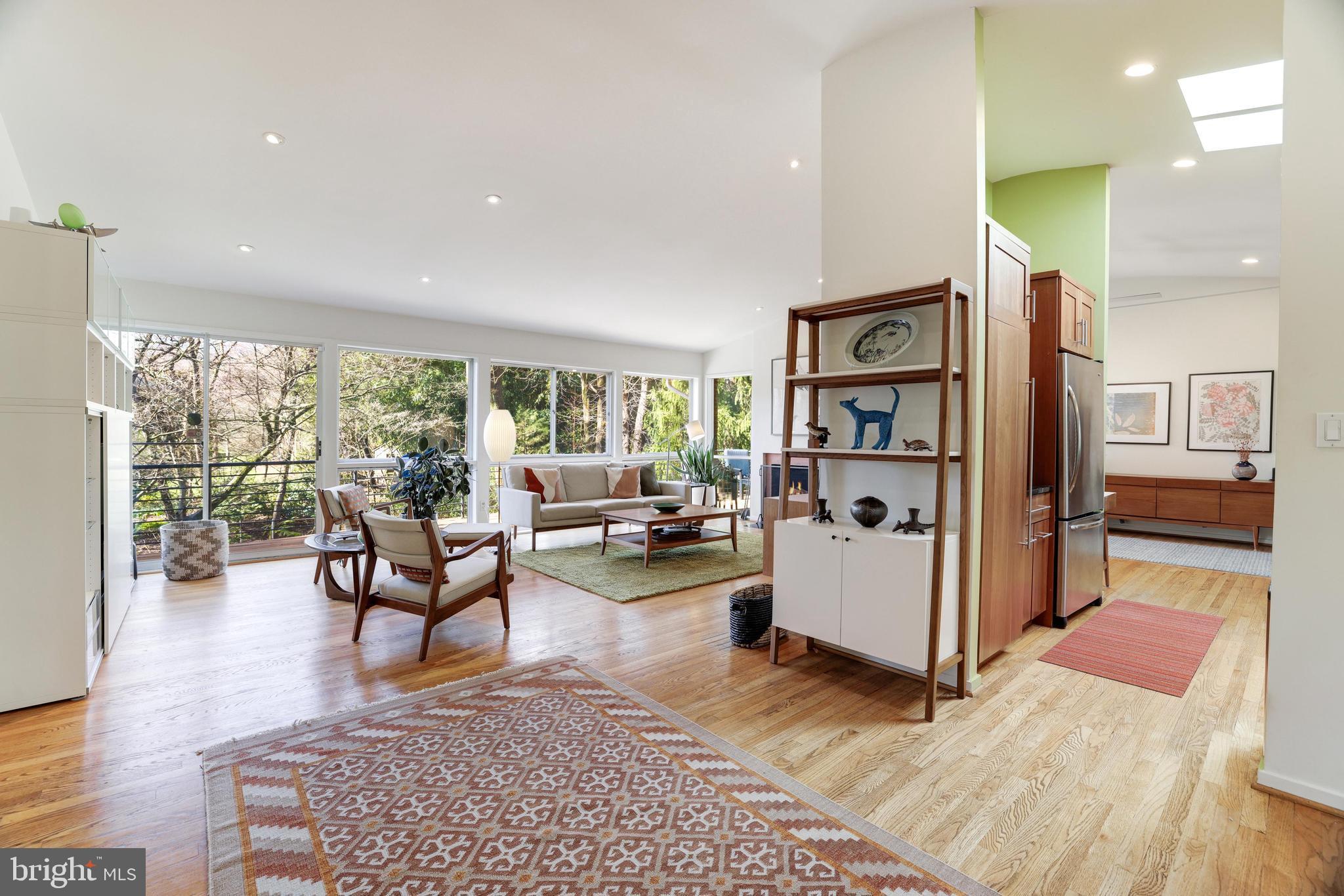 Welcome to 8216 Lilly Stone Drive, a remarkable mid-century modern Glenmore model home in the sought-after Carderock Springs neighborhood of Bethesda. This unique and rarely on the market model features 5 bedrooms and 3 bathrooms, standing out as one of the few models where you walk in on the main level, offering convenience and accessibility. The main floor hosts the primary bedroom with an ensuite bath along with two additional bedrooms and a bath.

Upon entering this main level, prepare to be captivated by the renovated and expanded living/dining/kitchen area, boasting a pitch high ceiling adorned with delightful skylights. A magnificent wall of glass, comprised of windows and sliding doors, floods the space with natural light and offers picturesque views of the beautifully landscaped backyard. Adjacent to the sliding doors is a charming nook, perfect for an office space, leading to a wonderful Trex deck with great entertaining space and stairs that descend to the enchanting backyard, featuring a charming tree house—and another ideal setting for entertaining guests. Additionally, the dining room boasts an oversized picture window, allowing you to savor your meals while feeling immersed in nature.

Downstairs, a spacious family room with sliding doors opens up to the backyard, creating a seamless indoor-outdoor flow. Additionally, the lower level boasts two more bedrooms, a laundry room, and a full bath, offering ample space and versatility.

This home includes a one-car garage, perfect for both parking and storage needs.

Nestled in a vibrant community, residents enjoy access to the Carderock Springs Swim and Tennis Club, proximity to the Bethesda coop, and a variety of dining options on Macarthur. Furthermore, the home is conveniently located near Potomac Village, offering the perfect blend of convenience and charm. Moreover, the neighborhood's inclusion in the National Historic Registry underscores its timeless appeal, while covenants, an architectural board, and a tree committee contribute to the preservation of its unique character.