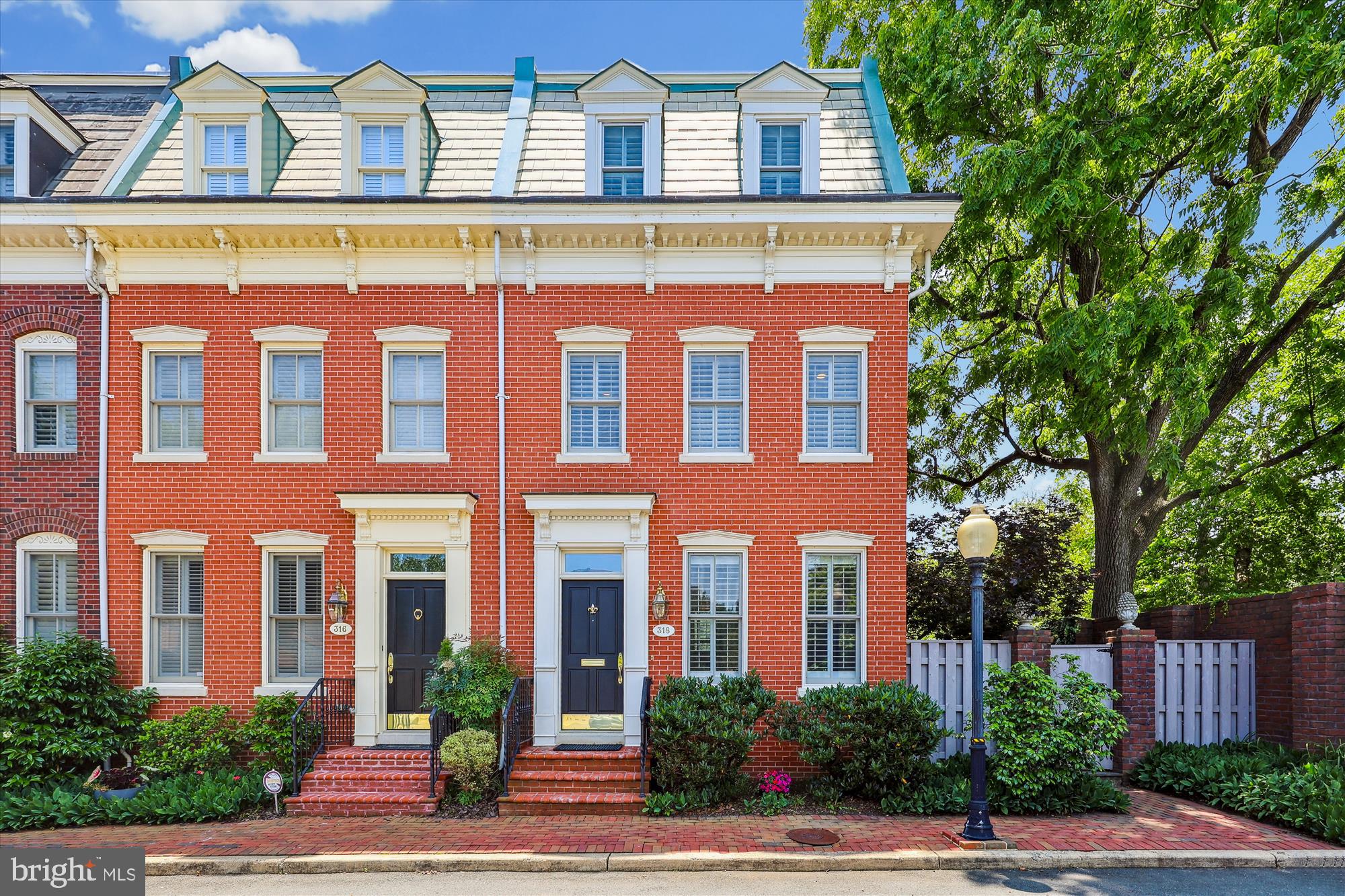 Rarely available and highly sought-after, this stately four-level brick townhouse in Fairfax Row offers the perfect blend of timeless elegance and modern luxury. Featuring 3 spacious bedrooms, 3 full baths, arched entryways and a finished lower level, this home is designed to impress from the moment you step inside.
The gourmet kitchen is a chef’s dream, boasting top-of-the-line Wolf appliances including a 4-burner cooktop with hidden exhaust, convection microwave, wall oven, and a Liebherr counter-depth refrigerator. Granite countertops with barstool seating and ample prep space make it ideal for both cooking and entertaining. A formal dining room and an inviting living room, complete with custom built-ins, mantled fireplace, and elegant moldings, offer multiple spaces to gather and unwind. This thoughtfully designed home features three bedrooms across the two upper levels offering privacy and versatility for families or guests. There is even a separate dressing room complete with custom built-ins—perfect for a stylish, organized start to your day. Natural light floods the interior through large, strategically placed windows, and top floor skylight and sun tubes, creating a warm and airy feel throughout. Enjoy the convenience of a full-size laundry area upstairs and ample storage space. On the lowest level don't miss the recreation area, ideal for a casual night of TV, a home gym, the options are endless. This home blends smart design with comfort in every corner, to include a seldom found Electrolux Central Vac system. 
Perhaps the pièce de résistance is the wraparound brick patio, a truly unique feature that stands out especially in charming Old Town Alexandria with plenty of space to grill, dine and entertain on a grand scale. Additional highlights include two assigned private parking spaces, plus guest parking, a rare and valuable find. Ideally situated for the discerning buyer seeking both convenience and lifestyle, this home offers an unbeatable location. Just a short stroll to the Potomac River, scenic parks, bike paths, popular dining spots, grocery stores, coffee shops, and vibrant nightlife, plus the city trolley is nearby for easy local access. Commuting is a breeze with two Metro stations just over a mile away, the DASH bus at your doorstep, and quick routes to Reagan National Airport, the Pentagon, and Downtown D.C.