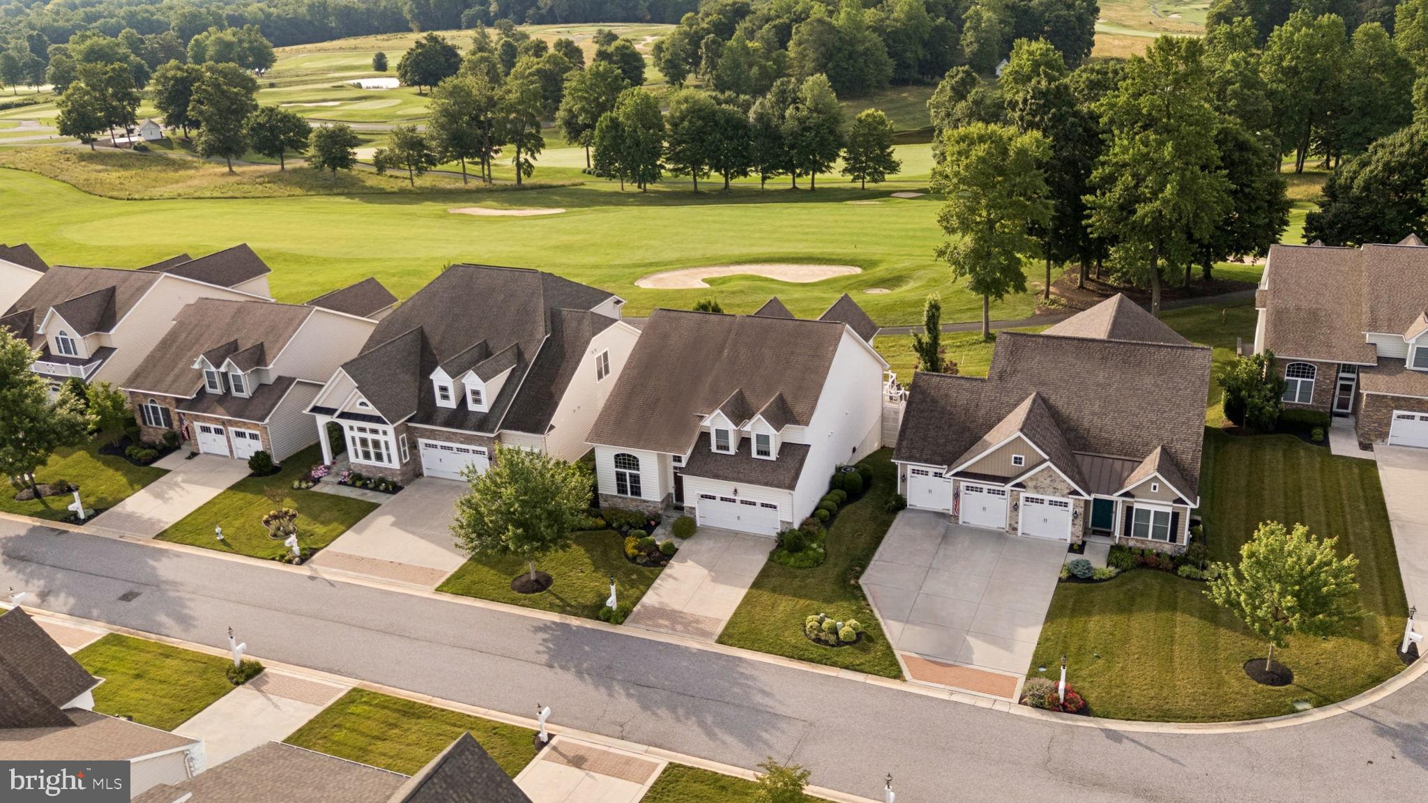 Experience luxury living right on the greens! Located in the highly sought-after Bulle Rock community, this stunning 5-bedroom home backs directly to the 1st hole of the nationally-ranked Bulle Rock Golf Course, making it an absolute dream for golf enthusiasts. Step out onto the large composite deck or relax on the rear paver patio featuring a curved sitting wall and fire pit to take in the spectacular course views. Inside, the main level impresses with hardwood floors, gorgeous wainscoting, and a living room featuring a gas fireplace, a unique barrel ceiling with up-lighting, and sliders perfectly framing the golf course views. The gourmet kitchen is equipped with a breakfast area, granite countertops, an island with seating, and premium Wolf appliances. The convenience of a main-floor primary suite is enhanced by a tray ceiling, a walk-in closet, and a luxurious bath with a soaking tub and an expansive floor-to-ceiling tiled shower. The upper level offers a versatile loft, a second primary bedroom suite with a private bath, and another bedroom boasting elevated views of the golf course alongside glimpses of the Chesapeake Bay. The walk-out lower level, updated with new carpet in 2026, is built for entertaining with a family room, a bar counter with a beverage fridge, and a dedicated theater room prepped for a projector. The Bulle Rock community features resort-style living, offering residents access to a luxurious community center, indoor and outdoor swimming pools, a fitness center, tennis courts, walking trails, and gated entry. Don't delay, visit this unique property and make it yours today.