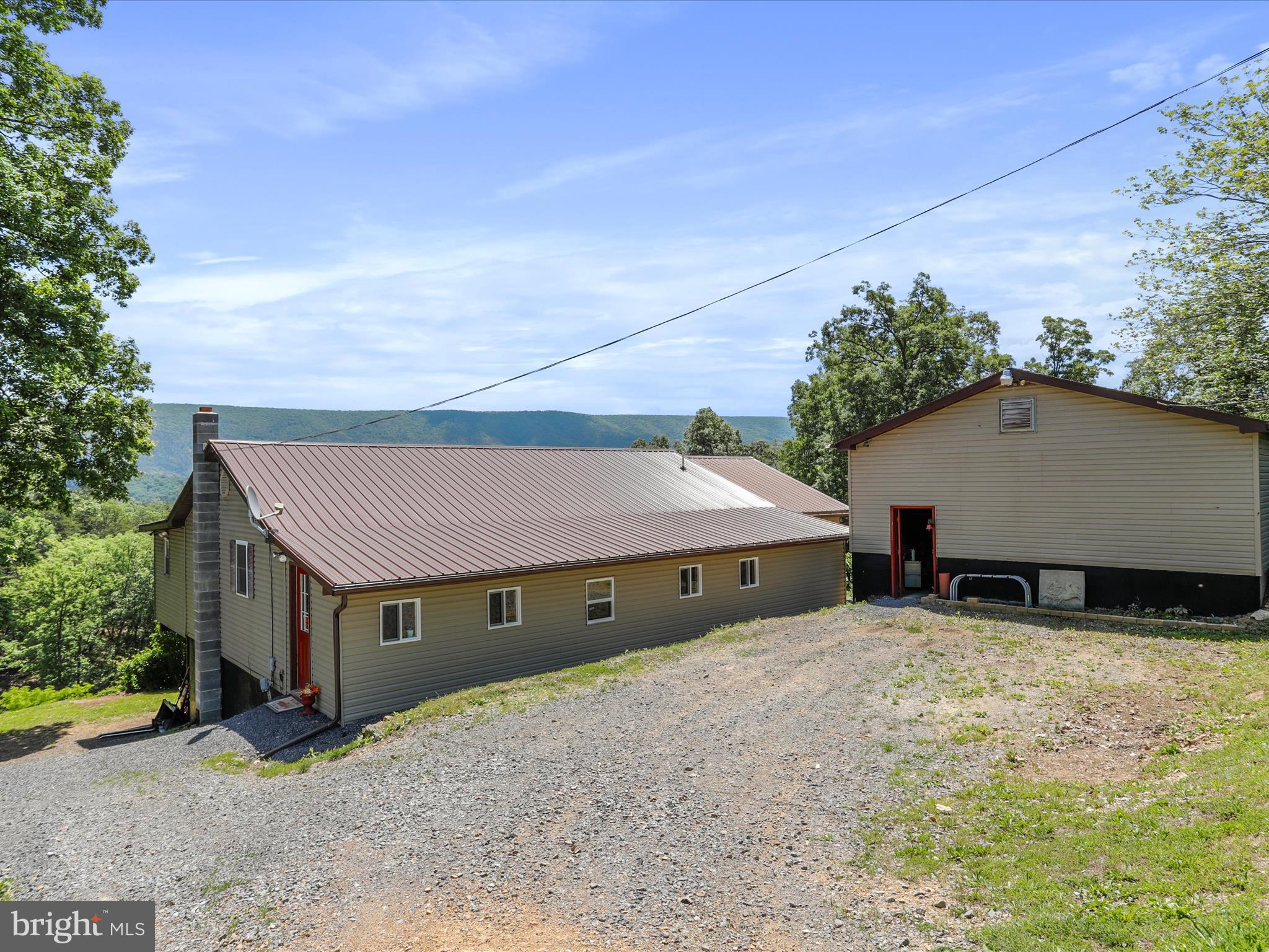 Big price reduction!!!  Imagine a cozy home nestled in the mountains of West Virginia. Whether you are seeking self-sufficiency, homesteading, relaxation, or adventure, this property offers the perfect blend of tranquility, outdoor enjoyment and convenience.   This spacious custom-built rancher is handicapped accessible with amazing mountain views sits on two lots totaling 11.58 acres. (Two adjoining 5.79 acre lots).  Second lot has well, septic and electric, perfect to add another garage, barn or home.   House has new metal roof, gutters and downspouts, installed in 2024, central air, heat pump, wood stove and maintenance free water treatment system.  The Rose of Sharon bushes that line the front of the property along the road offer added privacy and beauty.  There is a garage and several outbuildings including the "Treehouse" featuring a hot tub and deck with spectacular views.   Bring your ATV and ride the trails throughout the property.  Enjoy the abundant wildlife with a pond and great hunting right from your own back yard!!  Plenty of room for a nice garden too.  Located just minutes down the road from the Cacapon River for floating, fishing and swimming.    Enjoy country living while just living minutes from Berkeley Springs. Easy access to hospital, grocery, restaurants, and more. Enjoy the antique mall shops, and short trips to Cacapon Resort State Park, or take a historic walk at Prospect Peak and so much more. No HOA, light deed restrictions, $25/year/lot road maintenance.   Hunting/shooting/ manufactured homes/ATVS are permitted. Call today for your appointment to see this unique property.