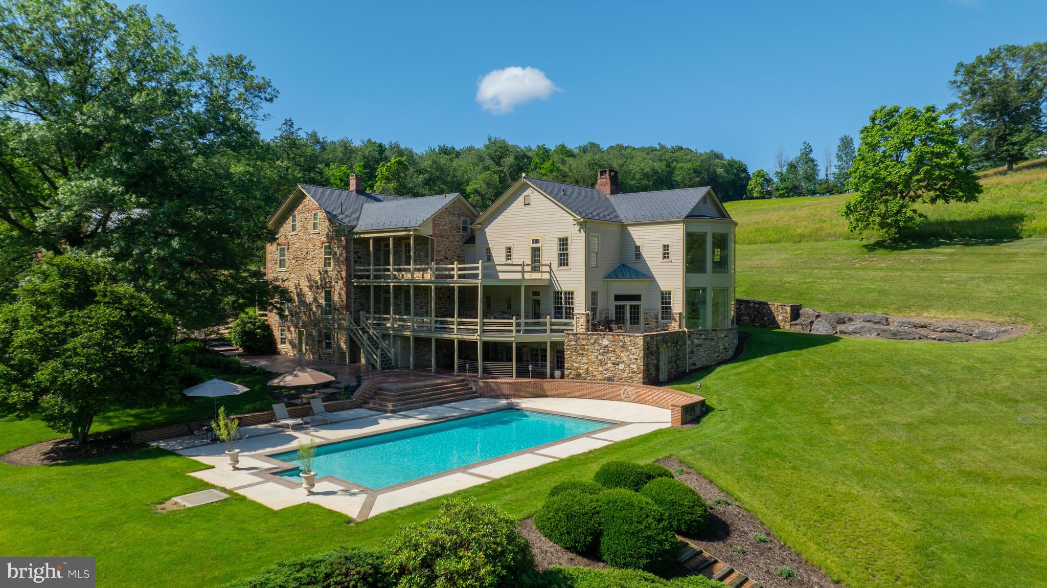 Welcome to your executive retreat — a one-of-a-kind estate offering the ultimate in privacy, space, and sophistication. Nestled on 68 pristine acres in the east end of York County, this extraordinary property is the perfect sanctuary for discerning buyers who value both seclusion and elegance. From the moment you enter the 1,000-foot long driveway, framed by immaculate landscaping and breathtaking stonework, you’ll know you’ve arrived at a property unlike any other.

The 10,000+ square foot residence seamlessly blends timeless farmhouse charm with modern luxury, having been thoughtfully expanded and updated with the highest level of craftsmanship. Inside, you’ll find an open and airy layout designed for entertaining and showcasing — ideal for hosting large family gatherings or intimate gatherings with your friends. The grand great room is a true centerpiece, boasting 20-foot ceilings and a dramatic wall of windows that frame stunning views of the natural surroundings.

The gourmet kitchen is a chef’s dream, featuring expansive granite countertops, custom cabinetry, and premium appliances — all designed to impress and inspire. Throughout the home, every window offers a picturesque view: from the serene, oversized stocked pond to the lush grounds where deer, wild turkeys, and foxes roam freely.

The second level presents two luxurious owner’s suites, plus a versatile bonus room currently used as a premier office — perfect for the executive working from home in style. The finished lower level provides even more flexibility, ideal for a guest or in-law suite with private access.

Car enthusiasts and collectors will be thrilled with the array of outbuildings and garages, offering ample space for vehicles, recreational equipment, or a private workshop — all without the worries of bothering your neighbors. The inviting in-ground pool completes this extraordinary offering, delivering resort-style relaxation just steps from your door.

This estate is positioned perfectly in York County in that you have easy access to Rt 30, Sam Lewis State Park and all the many attractions that both York and Lancaster Counties have to offer!

This is more than a home — it’s a lifestyle. A rare opportunity to own an unparalleled property that offers privacy, luxury, and room to dream. Come experience it for yourself — you’ll fall in love at first sight.