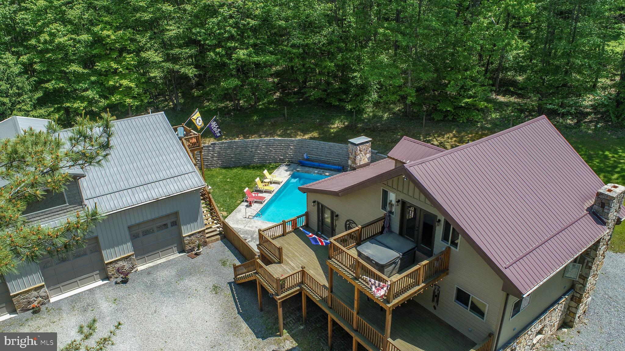Recently updated in 2021, this home features modern finishes, premium hardwood floors, and upgraded systems throughout.  The apartment above the garage offers an additional 3 bedrooms and 1 full bathroom. Located next to Wisp Resort and Fantasy Valley golf course, this property is just minutes from everything Deep Creek Lake has to offer! Step into your private oasis featuring an incredible outdoor patio with a luxurious saltwater pool. The patio is complete with a hot tub, a wood burning fireplace, outdoor bar, and plenty of lounge seating. It's resort style living right in your own backyard. The main house is 4 bedrooms and 3 full bathrooms with just under 3,000 square feet of living space. The kitchen features top-of-the-line appliances, custom cabinetry, and an island perfect for setting up food. Designed for both style and function, it’s a chef’s dream—where gourmet meals and everyday living come together effortlessly. The primary bedroom features a hot tub on the balcony, perfect for a relaxing movie night. All bathrooms have been beautifully updated and appointed. Downstairs is the perfect place to enjoy any sports game. There is a game table, pool table and a second living room perfect for game night! The massive 38ftx50ft (2,272 sq ft) heated garage offers so much space for storage or a workstation with an apartment/in-law suite above. The sellers currently have the space above the garage setup as a 3 bedroom and 1 full bathroom and are renting it through Airbnb. This property is located outside of zoning, so the new owner can decide what they wish to do with this amazing space! Please contact me today to schedule a private tour of this McHenry oasis! This property features a video and audio security system.