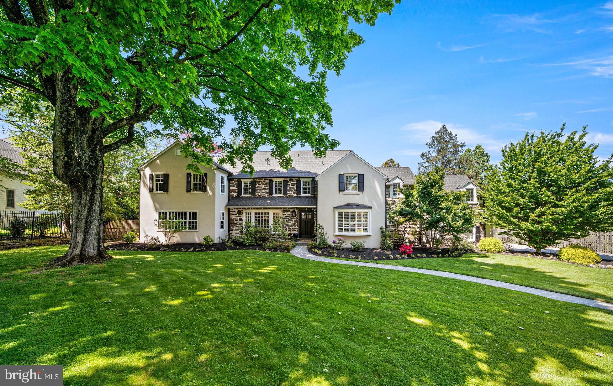 Welcome to 1208 Waverly Road, a stately stone Colonial nestled  in the heart of sought-after Gladwyne. Set on a  on 0.72 manicured acres, this sunlit 6 bedroom, 4.5 bath residence offers the thoughtful updates and modern comforts sought by today’s buyers.
A charming flagstone path leads to the front door and open foyer. To the left, the formal living room features a marble-surround wood-burning fireplace, flanked by custom built-ins. A beautiful bay window fills the space with natural light and offers serene views of the private front yard, while glass-paneled french doors provide access to the rear patio. Just beyond, a den/playroom with built-ins and backyard access. Glass-pane pocket doors open to the renovated library, which features a wall of new built-in shelving, new lighting, dual built-in desks, and a charming window seat.
The formal dining room wraps along the rear of the home, highlighted by a large bay window for abundant natural light. Designed with both style and function in mind, the open kitchen boasts marble countertops throughout, a large center island with seating, stainless steel GE appliances including a six-burner stove and beverage refrigerator, glass-front cabinetry, and space for a breakfast table overlooking the family room.
The family room features a second marble-surround wood-burning fireplace, custom built-ins and is bathed in natural light from the walls of windows and sliders that lead to the rear patio. This space also provides access to the three-car garage and a secondary staircase leading to a private au pair/guest suite. Completing the main level are a freshly renovated powder room and a charming home office.
Upstairs, the primary suite offers vaulted ceilings, a newer large picture window, dual walk-in closets, and a well-appointed en suite bath with a double vanity, oversized walk-in shower, and separate soaking tub. Four additional generously sized bedrooms share two full hall baths. The guest/au pair suite, accessed via its own staircase, includes two additional bedrooms and a full hall bath—ideal for visitors or extended family.
The partially finished basement provides a flexible secondary living or entertaining space, while the unfinished portion offers abundant storage. 
Outdoors, enjoy a beautiful bluestone patio overlooking the fully fenced backyard, surrounded by mature landscaping that creates a peaceful and private oasis. A full-house generator adds an extra layer of convenience and peace of mind. 
Just steps from Saunders Woods Preserve and located within Lower Merion’s award-winning school district, this home offers an ideal combination of setting and convenience—paired with classic architecture, thoughtful updates, and well-designed living spaces both inside and out.