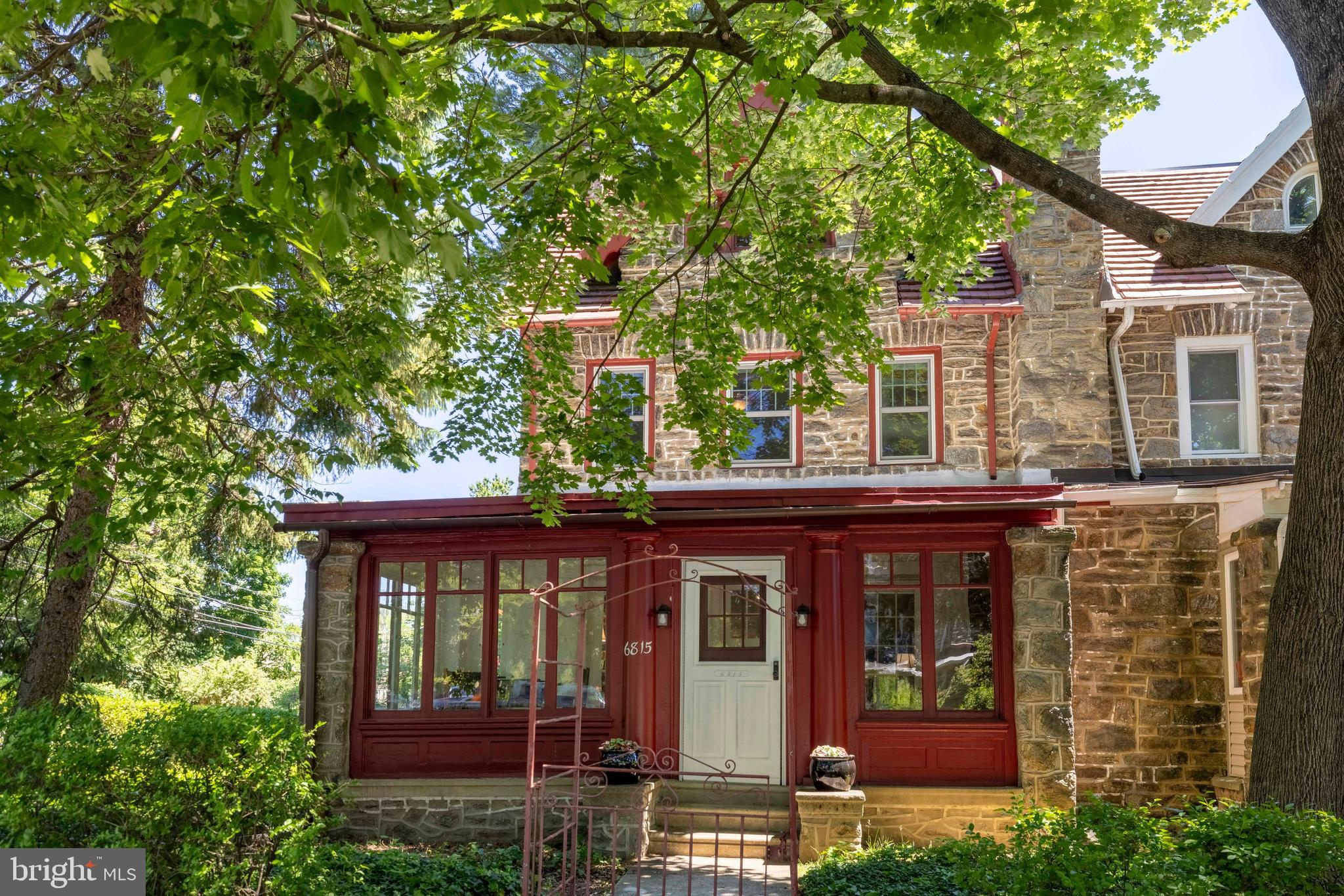 Just listed! This handsome C 1925 three-story, five-bedroom, four-bathroom stone twin on a corner lot is one block from the coveted, vibrant, and welcoming Mt Airy Village.  Situated in the heart of West Mount Airy, one of Philadelphia’s highly regarded neighborhoods, you do not need a car.  Coffee, milk, food, or peace of mind is a short walk away: one block to Weaver’s Way Co-op and High Point Cafe, then a few more blocks to the Wissahickon or Carpenters Woods (a fave for birders).  The R8 regional Line or the 71 or 23 bus routes are within walking distance.  Move- n time for the September Mt Airy Fair. 
Many original interior architectural details are intact: archways, a skylight, classic 12-lite French doors, built-ins, wood floors, and more, adding to the charm of the home.
If you enter from the front door on McCallum Street, you are welcomed into a spacious light-filled enclosed porch with a stone fireplace. Or enter from the Carpenter Lane side walkway to another light-filled enclosed porch that serves as a mudroom/pantry/rear entrance to the kitchen.  Either way, you will find yourself in a warm, light-filled first floor: a remodeled eat-in kitchen, a dining room, and a lovely living room with a fireplace. The second floor has two en-suite bedrooms: one with a dressing room and the other with a more recently remodeled full bathroom.   The third floor has 3 bedrooms and a hall bath with a claw-foot tub. Ample closets throughout.
Off the kitchen is the stair to the basement, which has a bathroom, laundry room, lots of closets, and a rear door to the backyard and garage. The garage is entered from a common drive in the rear, and has a transponder for remote opening.  Don't miss the perennial gardens and flagstone patio in the fenced-in rear yard. The mature trees have been lovingly cared for.