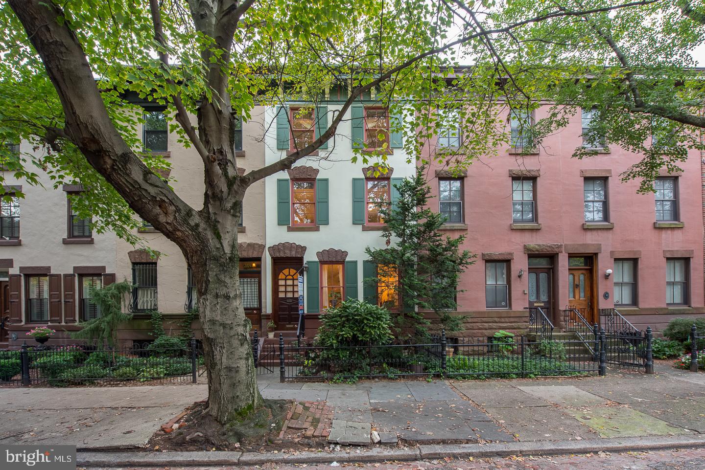 Tucked away on an idyllic, tree-lined block in Philly’s iconic Fairmount neighborhood sits 2126 Green St. This beautiful and historic row home offers 3 bedrooms, 2.5 bathrooms, a finished basement, and garage parking, plus a tax abatement through 2027. A lush, gated yard welcomes you from the street. Inside, hardwood floors run through the large living room, anchored by a fireplace and wooden mantle. Detailed millwork is displayed in the crown molding, window trim, door trim, and staircase. Down the hall, past a powder room, you’ll discover the heart of the home, the gleaming chef’s kitchen. Adorned with high-end stainless steel appliances, granite countertops, subway tile backsplash, inset cabinets, and a breakfast bar, this is sure to be the space everyone gravitates to, along with the adjoining dining room. At the rear of the home, there's a large deck surrounded by a privacy fence and trees. This serene oasis is destined to be your go-to spot for entertaining and relaxing on cool spring days and warm summer nights. The home’s lower level has a finished basement, ideal for a media room, den, or playroom, and a storage area. An extra-wide staircase, original to the home, takes you to the second level. Here you’ll find the home's large primary bedroom with hardwood floors, exposed brick walls, tall windows, and a fireplace flanked by built-in shelves. Also on this level, you’ll find a bedroom suite with a walk-in closet and a spa-like bathroom with a double vanity, clawfoot soaking tub, and a rainfall shower. This home is completed by a third-level dedicated to a spacious guest suite. In addition to all 2126 Green St offers inside, this location is a walker’s paradise with a Walk Score of 94! Famous Fairmount Ave, lined with local favorites including Cantina "Calaca" Feliz, Urban Saloon, and Thirsty Dice, is just a couple blocks north. Essentials shopping including Whole Foods, Target, and CVS are just a few blocks south. Plus landmarks like the Philadelphia Museum of Art, Kelly Drive, Schuylkill River Trail, and the Eastern State Penitentiary are nearby too. There’s also easy access to I-76, I-676, and University City. Schedule your in-person or virtual tour today!!