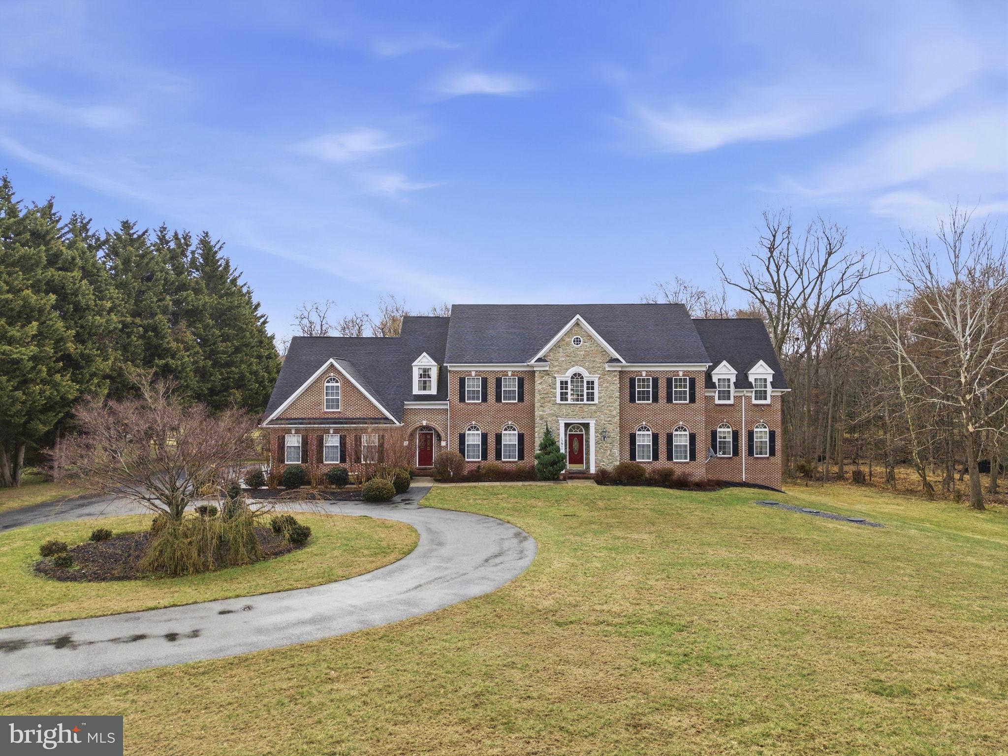 Set on an expansive and private lot, this extraordinary custom-built residence spans three finished levels, offering abundant space for both sophisticated entertaining and everyday living. A two-story grand foyer with marble floors and a sweeping curved staircase welcomes you, setting the tone for the elegance throughout. The main level features a formal dining room highlighted by columns, chair rail, and wainscoting, perfectly balanced by a spacious living room that flows seamlessly into an inviting sitting area and a private office—creating a thoughtful progression of living spaces. At the heart of the home, the gourmet kitchen features an L-shaped island with cooktop and hood, a breakfast bar, abundant cabinetry, double wall ovens, and a large bay window above the sink that fills the space with natural light. Off the kitchen, a generous deck overlooks the property, enhancing the indoor-outdoor lifestyle. The kitchen opens directly to the family room, where a stone accent wall with a gas fireplace anchors the space. A wet bar with a mini fridge adds a perfect touch for entertaining. The main-level primary suite includes a full bath and ample closet space, ideal for guests or multigenerational living. Upstairs, the primary suite is a true retreat, featuring vaulted ceilings, a private sitting room, a large walk-in closet with custom built-ins, and additional separate closets for abundant storage. The spa-inspired primary bath is elegantly appointed with a soaking tub, dual vanities, and a walk-in shower, creating a serene and luxurious escape. All upper-level bedrooms include private baths, while an office, hallway storage, and conveniently located laundry combine elegance with everyday practicality. The finished lower level offers two additional bedrooms, a full bath, a recreation room, an exercise room, and a sitting area, with walk-out access to the patio and backyard. The home is fully equipped with a built-in fire suppression system, intercom, and alarm system. A three-car oversized garage and two separate entryways further enhance the home’s functionality, completing this exceptional residence that seamlessly blends luxury, comfort, and timeless design.