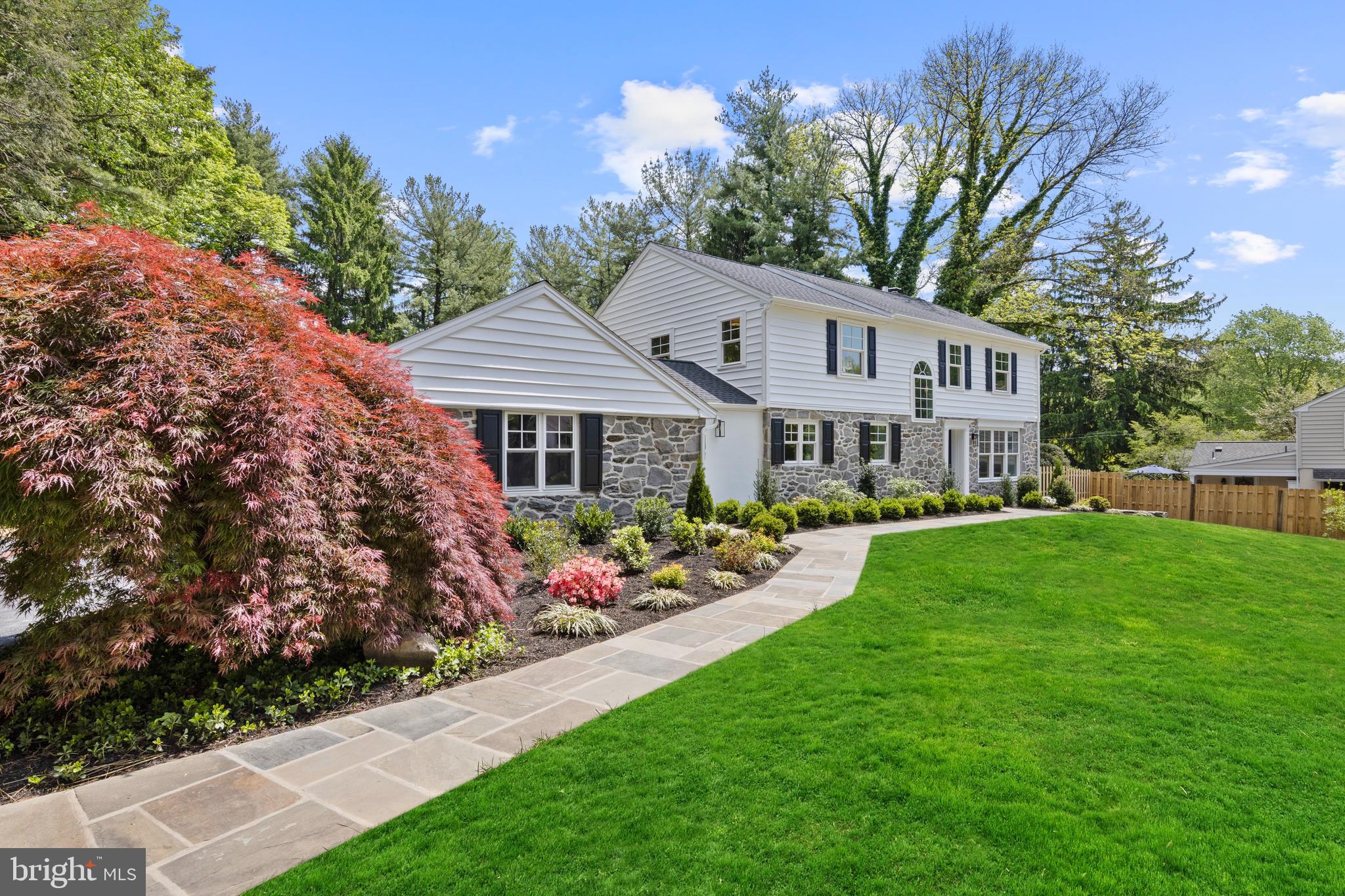 1611 Lark Lane, Villanova — Completely reimagined and renovated inside and out, this exceptional 4 bedroom, 4 full and 1 half bath home blends the comfort and functionality of a newly built luxury residence with the timeless charm of its stone exterior and sought-after neighborhood setting. Situated on an almost one-acre level lot on a private cul-de-sac street within the top-ranked Lower Merion School District, this move-in ready home showcases high-end finishes throughout all three finished levels.
The home’s curb appeal impresses with beautiful original stonework, inviting arched breezeway, and extensive exterior improvements including new roof, gutters, windows, siding, shutters, Therma-Tru exterior doors, driveway, flagstone walkway, refreshed landscaping and lawn.
Enter into the welcoming foyer featuring rich-toned refinished hardwood floors that are throughout most of the home. A dramatic arched window illuminates the redesigned staircase with new railings and spindles, beadboard accents, and designer sconces. The home also features all new interior and exterior doors, trim work, fresh neutral paint, and designer lighting throughout.
Fully renovated with exceptional attention to detail, every inch of this home was redesigned for today’s lifestyle. Reimagined spaces created an open living area centered around the family room, chef’s kitchen, and breakfast room. The beautiful windows allow loads of natural light throughout the home.
The family room features updated arched built-ins, recessed lighting, fireplace with new gas insert, and wall of windows overlooking the private rear setting. The chef’s kitchen includes an 11-foot island with seating for five, 3-inch Calcutta countertops, Calcutta backsplash, white shaker cabinetry with pantry storage, gold hardware, recessed lighting, dry bar with glass-front cabinetry, and premium appliances, including Liebherr paneled refrigerator, Thor 6-burner range with griddle, paneled dishwasher, beverage refrigerator, and microwave drawer. The breakfast room is a true showstopper featuring a statement chandelier and custom banquette seating for ten surrounded by windows on three sides. Sliding doors connect beautifully to the rear slate patio. 
Additional main level highlights include a formal dining room, which could also serve as an impressive office, off the foyer with triple front windows and deep sills. A long front hallway leads to an elegant powder room, private library room with French doors, and huge mudroom with slate flooring, built-in cubbies, bench seating, storage cabinets, and two large closets. A side entrance opens to the breezeway and attached two-car garage.
Upstairs, the primary suite offers peaceful views and exceptional storage with two closets anchored by a window seat plus an additional walk-in closet. The marble ensuite bath features marble tile flooring, soaking tub, oversized walk-in shower with Hansgrohe fixtures and massage settings, double fluted vanity with built-in hair dryer drawer, and water closet. The newly installed second ensuite bedroom includes its own marble bath, adding another full bathroom to the home. Bedrooms three and four share a renovated hall bath with marble floor, bathtub plus double sink vanity. A second-floor laundry with built-in storage is conveniently located off the spacious hall.
The fully finished lower level features newly installed light-toned LVP flooring and flexible living space including a large bonus room with refreshed full bath, yoga / workout room, utility room with sink, and additional storage space.
Outside, the fenced in-ground pool updated in 2024, flagstone patio, and landscaped rear yard create the perfect outdoor retreat. Additional updates include new HVAC and garage doors (2024),  
Conveniently located near Villanova train station, shopping, dining, and major commuting routes, this move-in ready home offers the very best of Main Line living.