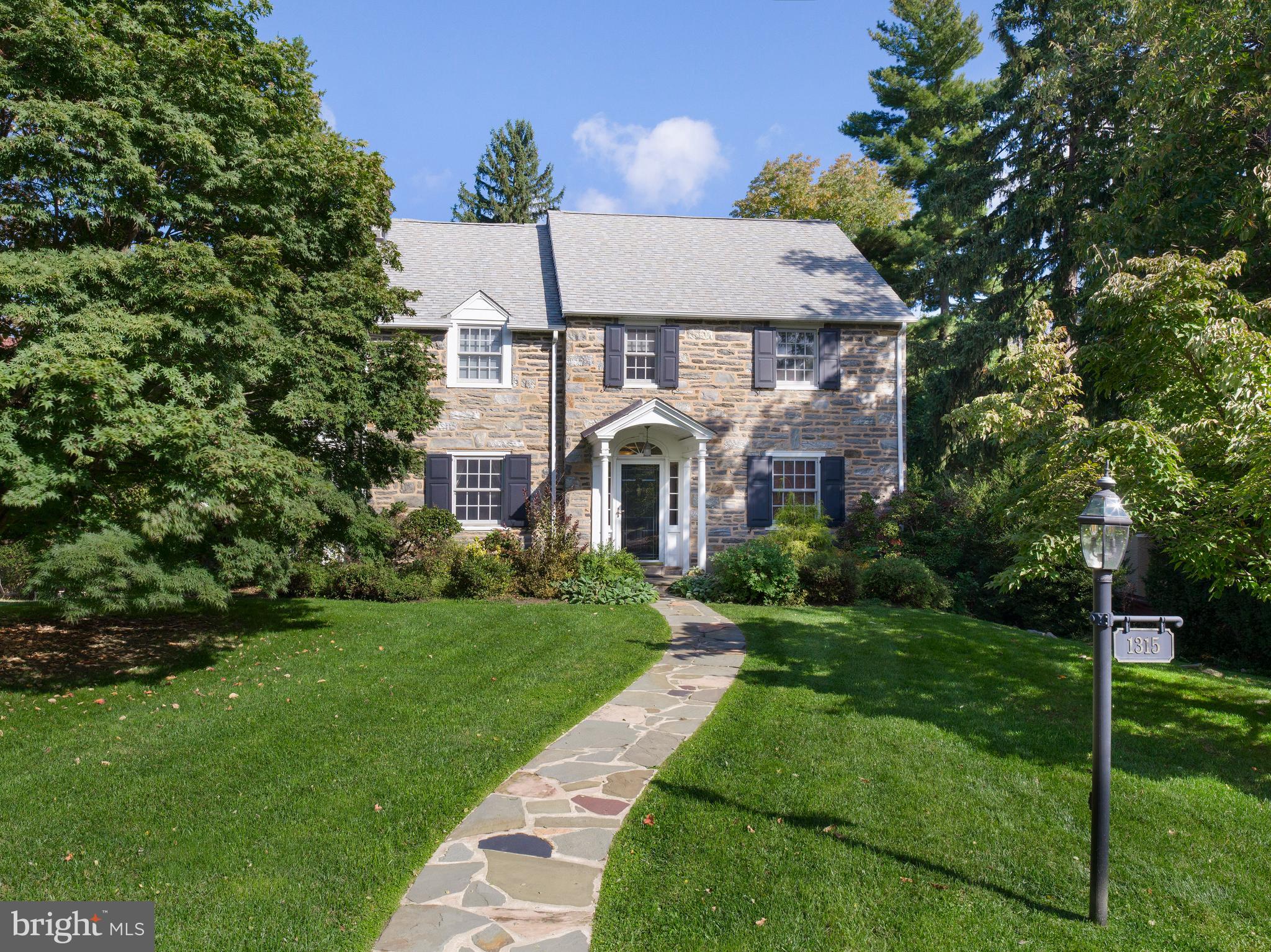 This stunning stone Colonial seamlessly blends classic charm with modern living, thanks to a thoughtful two-story expansion that enhanced both functionality and character. The addition introduced a spacious eat-in kitchen and great room, creating a natural gathering place filled with warmth and light. Upstairs, a luxurious primary suite was added, offering a private retreat with generous space and comfort. A new dormer enhances the roofline, bringing in additional light, while the expansion also included a garage, providing both convenience and practicality.

Designed for both everyday living and effortless entertaining, this home features an open, flexible layout that easily accommodates everything from quiet moments to large gatherings. The chef’s kitchen is a standout, with two ovens, a six-burner cooktop, two dishwashers, and two sinks—ideal for both entertaining and a kosher kitchen. Over the years, this home has hosted events ranging from small dinners to lively celebrations with up to seventy-five guests, creating an atmosphere of warmth and connection.

The outdoor spaces are equally impressive. A large deck with Ipe Wood Decking sits high above the backyard, offering stunning views and the perfect spot for morning coffee or quiet evenings. The sprawling yard features a thriving garden, producing fresh tomatoes, zucchini, kale, and herbs all summer long. An outdoor fire pit has been the setting for countless nights of s’mores and laughter, bringing loved ones and friends together under the stars.

Inside, the home is designed for both shared experiences and personal retreat. The sunroom, porch office, and multiple living spaces provide the perfect balance of togetherness and privacy. Spacious bedrooms offer comfort and generous closet space, while the primary bathroom features radiant heat floors for a touch of luxury. The home’s stone construction naturally retains warmth in the winter and stays cool in the summer, enhancing both comfort and efficiency. A key feature is the dry basement, which has remained completely dry through every season.

Set on one of the largest double lots in the area, this home offers a rare combination of space and privacy in a highly sought-after neighborhood. The surrounding community is vibrant and welcoming, with a beloved annual block party bringing neighbors together. Its location is unbeatable, just moments from Whole Foods, Suburban Square, top-rated schools, parks, and easy access to SEPTA’s Regional Rail and High-Speed Line.