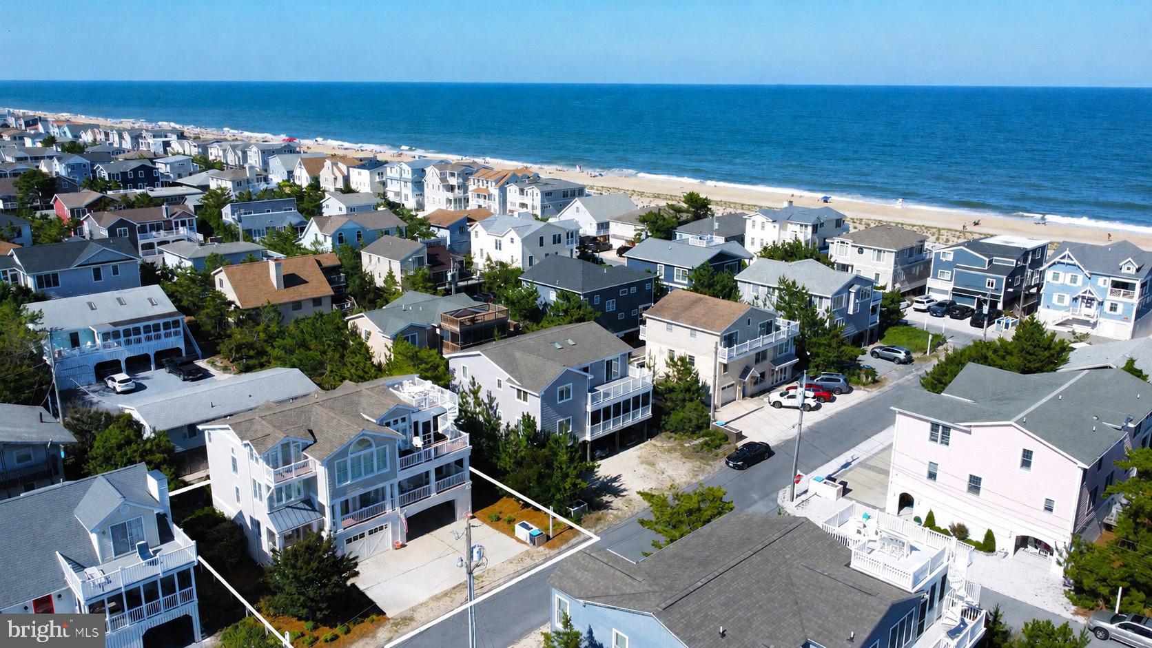Perfectly positioned just four lots from the ocean and only steps from the sand and surf, this exceptional coastal residence offers luxurious beach living in one of South Bethany's most desirable locations. Thoughtfully designed with an inverted floorplan to maximize natural light and capture glimpses of the ocean, the home is enhanced by an elevator servicing every level and exquisite custom millwork throughout. The upper level is dedicated to the home's impressive living spaces, where a dramatic vaulted ceiling and a floor-to-ceiling stone gas fireplace anchor the expansive great room. The open-concept design flows seamlessly into the dining area and gourmet kitchen, beautifully appointed with custom cabinetry, subway tile backsplash, stainless steel appliances including a gas range with hood vent, and a large center island with seating. Just beyond, a spacious screened porch and adjoining sun deck create an ideal setting for entertaining or relaxing, with stairs leading to a rooftop deck offering elevated coastal views. Also on this level is the spacious primary suite featuring a beautifully appointed ensuite bathroom with dual vanities and a walk-in shower accented by floor-to-ceiling tile, along with a convenient powder room and a charming elevated reading nook or home office. The lower level is designed for comfortable gatherings and overnight guests, offering a generous family room enhanced by a tray ceiling and elegant wainscoting, a dedicated laundry room, four spacious guest bedrooms, and two full bathrooms. This level also opens to a welcoming covered front porch, providing another inviting outdoor living space. On the ground level, a large storage room offers plenty of space for bikes and beach gear, while two outdoor showers make rinsing off after a day at the beach effortless. The expansive covered area provides exceptional flexibility for recreation or covered parking for up to five vehicles, complemented by room for four additional cars in the driveway. Ideally located in South Bethany, renowned for its wide, lifeguarded beaches and relaxed coastal charm, this exceptional property is just a short drive from downtown Bethany Beach, where boutique shopping, acclaimed restaurants, and the boardwalk await.