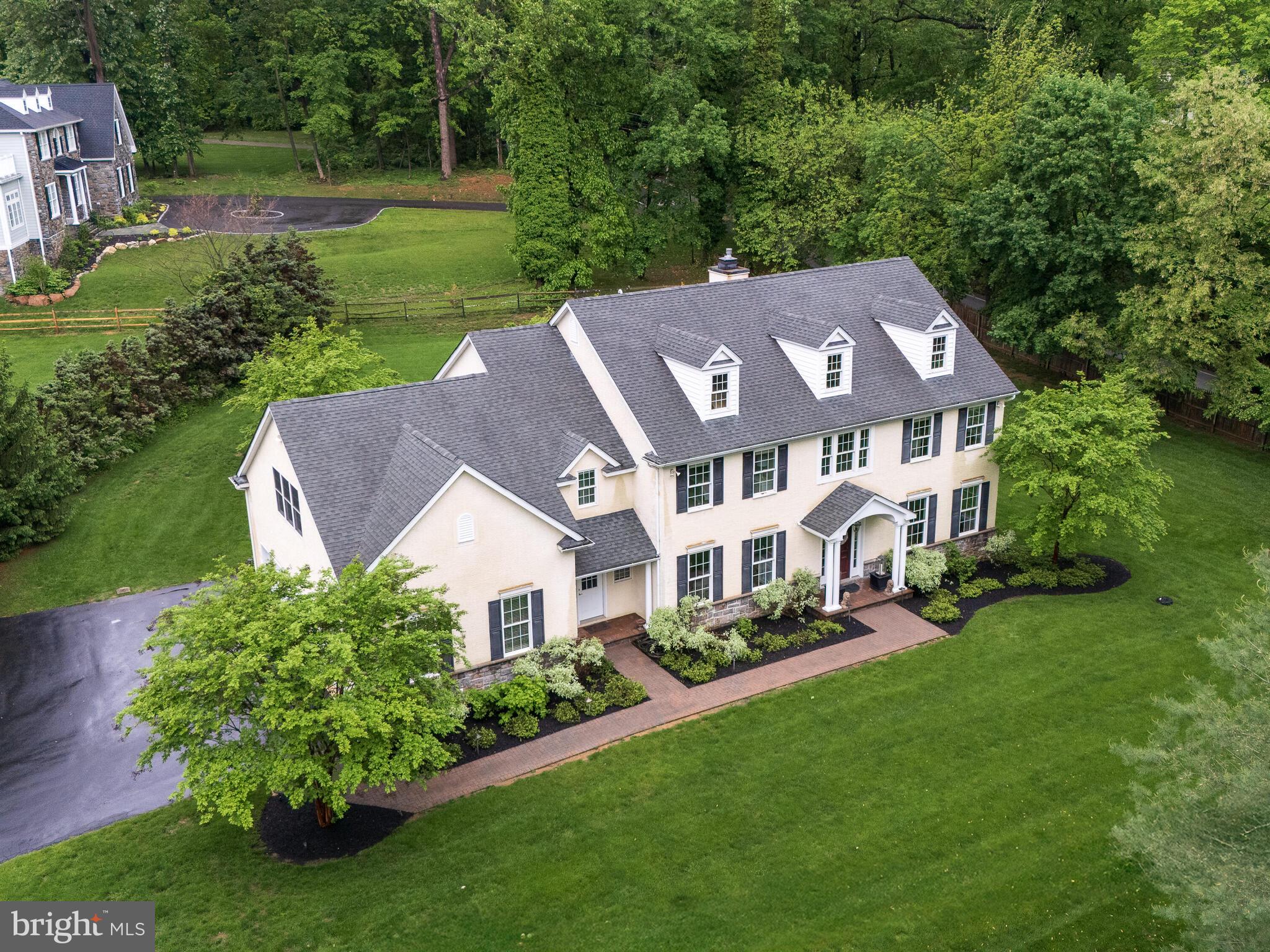 This exceptional custom residence, built in 2005, offers @ 4,593 square feet of thoughtfully designed living space with four bedrooms, four full baths, and two half baths, set on a beautifully landscaped 0.94-acre property in one of the Main Line’s most desirable locations. Situated on a prominent corner in a well-connected setting, the home provides outstanding access to major commuting routes while remaining just a quarter-mile from the Paoli train station and within the highly acclaimed Tredyffrin–Easttown School District (Beaumont elementary) —a rare combination that strongly supports long-term value and demand.Designed with presence and architectural character, the home’s stucco exterior contributes to its stately appearance. The property’s naturally sloped topography—both front and rear—enhances privacy, creates visual interest, and offers opportunities for creative landscaping, terraced gardens, or custom outdoor living spaces.A shared driveway arrangement, provides efficient access to the oversized three-car garage while preserving more usable yard space and maintaining the gracious setback of the home from the street.Inside, a grand two-story foyer with an open staircase and second-floor overlook introduces a residence defined by quality craftsmanship—gleaming wood floors, elegant crown molding, wainscoting, and abundant natural light. Thoughtful details include dual coat closets flanking the front entrance and large windows that frame views of the property from nearly every room.The open main level flows seamlessly from the formal living and dining rooms into a large kitchen featuring granite countertops, custom cherry cabinetry, an oversized island with seating for four, and a butler’s pantry connecting to the dining room. Stainless steel appliances and a rear staircase to the second floor enhance both functionality and design. A sunlit breakfast room with French doors opens to a private hardscaped patio—ideal for indoor–outdoor entertaining.The adjacent family room is a true centerpiece, boasting a cathedral ceiling, floor-to-ceiling windows overlooking the backyard, recessed lighting, a ceiling fan, and a gas fireplace. Nearby, a private study with glass French doors and walls of windows offers an ideal work-from-home space. Two conveniently located half baths on each side of the house, serve the main level, along with a spacious laundry/mudroom that provides direct access to the front walkway and the garage.Upstairs, the luxurious primary suite features a sitting area, two generous walk-in closets, and a spa-like bath with a soaking tub and separate shower. Three additional well-sized bedrooms are served by two full bathrooms, each offering ensuite access as well as hallway entry for flexibility.The fully finished lower level significantly expands the home’s living space, offering a second office, exercise room/flex room, fifth bedroom, full bath, and a stunning custom wet bar with seating for eight to ten—ideal for entertaining. A large open recreation area, a temperature-controlled wine storage closet, and a dedicated storage room for seasonal décor complete this exceptional level.Recent seller investments totaling $230,000 include custom interior lighting, new exterior hardscaping, professional landscaping, irrigation, and landscape lighting. The fenced rear and side yard and upgraded security system add privacy and peace of mind.Perfectly located near Main Line shopping, dining, parks, and transit—yet privately set on nearly an acre—131 Devon Road delivers comfort, craftsmanship, and convenience in a premier Paoli setting. Welcome home.