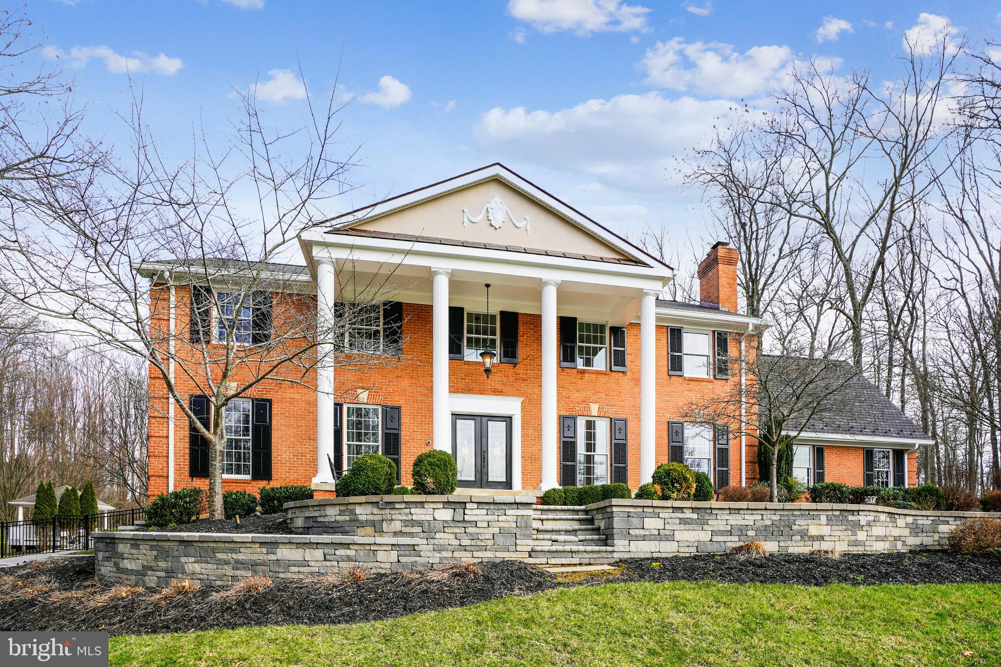 Welcome to this all-brick colonial situated high on 4.27 acres of manicured landscape, the perfect setting for its classic architecture, accentuated by statuesque 2-story columns and expansive portico.  Accent lighting highlights the extensive hardscape walls and walkways.  The 8000+ sqft of expansive living spaces showcase timeless upgrades, details and finishes.  A grand 2-story foyer features oversized molding, wainscotting, polished tile floor, curved staircase, and pocket doors for flexible access/privacy to adjoining spaces.  Elongated windows flood the formal living and dining room with natural light and picturesque views, enhanced by warm toned hardwood floors that carry through to the family room, and 15x24 gourmet kitchen.   Trending 2-toned 42"H cabinet, granite counters, 12ft island with custom bar height table and high-end appliance like 48" Subzero refrigerator and Miele built-in coffee system, this space was designed for functionality and entertainment with boundless lighting options.  The 20x30 sunroom with amazing views and direct access to the backyard amenities is a perfect backdrop for meals and family gatherings.  All 5 bedrooms are located on the second floor, including a primary bedroom with louvered shutters, ample space for a sitting area, huge walk-in closet, and a spacious bathroom with double vanity, shower and soaking tub.  The lower-level entertainment room with custom built bar is spacious enough to serve as a media, billiards and game room, elevating everything from family movie night to hosting sporting events thanks to hue programmable lighting, Sonos sound system and video matrix that perfectly synchronizes all 3 TV's at once.  Lower walk out opens to a hardscape patio and fenced wooded backyard with privacy and serenity to relax and enjoy time with family and friends.  Outdoor amenities include a saltwater pool, basketball court, gazebo and many tiered hardscape outdoor living spaces to complete your private retreat.  A bonus 30x50 detached cottage offers an additional 1200 sqft of living space,  full bath, and 1-car garage that can function as a pool house, office space, etc.