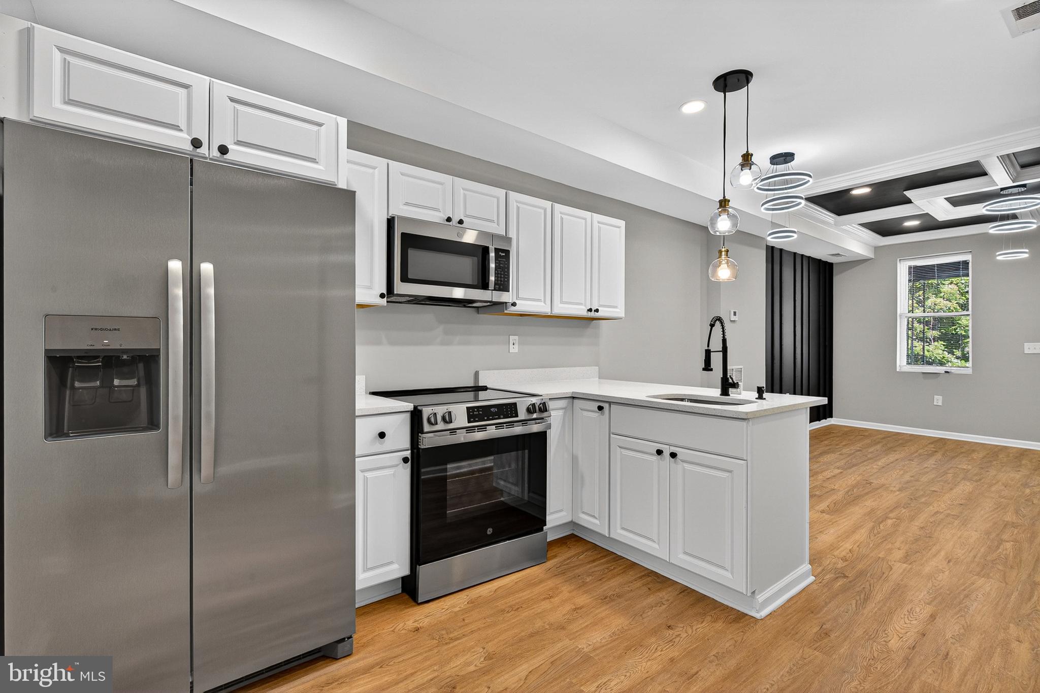 Perfectly reimagined and masterfully updated, this stunning 4-bedroom, 3-full-bathroom townhome delivers an exceptional blend of contemporary luxury and classic Baltimore charm. From the crisp, painted-brick facade and inviting covered front porch to the high-end interior details, no expense was spared in this top-to-bottom transformation.
Step through the striking black entry door into an expansive, light-filled main level featuring beautiful wide-plank flooring and soaring ceilings. The living area serves as a true showpiece, anchored by an exquisite coffered ceiling with deep black accents and custom, multi-tiered geometric LED chandeliers. A dramatic black vertical slat feature wall adds texture and high-end architectural interest.
The seamless flow leads you directly into the chef-inspired kitchen, meticulously designed for both casualGleaming white quartz countertops paired with a classic subway tile backsplash. Streamlined white shaker cabinets contrasting perfectly with a full suite of brand-new stainless steel appliances. A deep sink equipped with a professional-grade matte black spring neck faucet, overlooking a spacious breakfast bar.
An elegant staircase with a crisp white and black banister guides you to the upper quarters. Here, you will find bright, spacious bedrooms with generous closet space and excellent natural light. The bathrooms are styled with spa-quality finishes, featuring striking matte black plumbing fixtures, pristine custom tile work, and modern vanities that elevate your daily routine. The fully finished lower level expands your square footage significantly. Complete with its own beautifully appointed full bathroom, this level offers incredible flexibility to suit your lifestyle—perfect as a private fourth bedroom, an executive home office, a fitness studio, or a cozy media room. Brand-new HVAC system, updated electric, and energy-efficient recessed lighting throughout. Dedicated closet space with hookups ready for your choice of washer and dryer. Situated in an accessible Baltimore corridor, offering convenient access to local universities, commuter routes, downtown dining, and entertainment.
Every inch of this property has been curated to deliver a lifestyle of comfort and effortless modern elegance. Schedule your private tour today and welcome home!