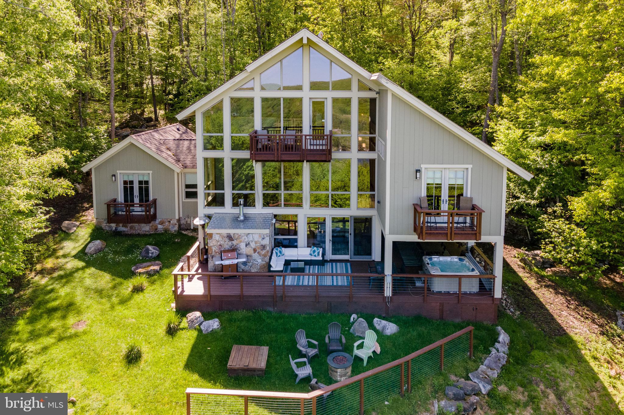 Perched atop a scenic mountain overlooking Deep Creek Lake, this stunning 5-bedroom, 5.5-bathroom home offers breathtaking views and ultimate privacy. Spread across multiple levels, the open-concept design features a grand living area with soaring ceilings, a stone fireplace, and large windows to take in the surrounding beauty. The gourmet kitchen, with top-tier appliances and a spacious layout, flows into both a formal dining area and an opening living space. The primary suite boasts a private deck, walk-in closet, and a luxurious spa-like bath. Each bedroom has its own en-suite for added comfort. Outside, a large deck with a hot tub and lake views invites relaxation. With lake access and your very own dock slip for boating, plus proximity to WISP  resort for skiing and winter fun, this home offers year-round recreation. Additional community features include: a private gated entrance, a seasonal outdoor pool, tennis courts, basketball courts, and a full lakeside area with ample parking, bathrooms, dock slips, & more. Whether for a family retreat or primary residence, this mountaintop gem offers the perfect blend of luxury, adventure, and serenity!