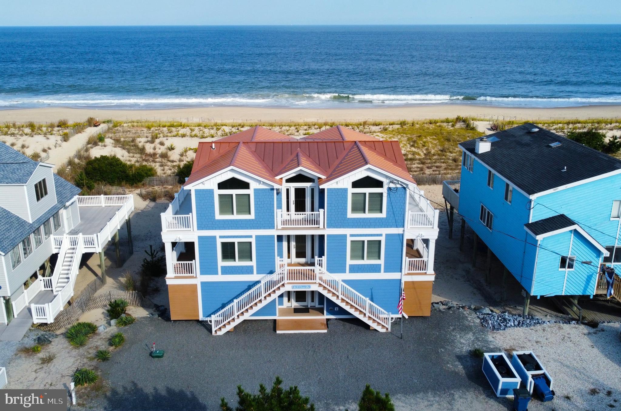 Oceanfront living at its best with expansive views of the coastline and easy access to the dune crossover just steps from the back door on this over-sized 70ft wide oceanfront property. This spacious home offers 5 en-suite bedrooms, each with its own entrance onto the impressive decks,  and an inverted floorplan with the main living area on the upper level to take full advantage of the incredible ocean views from window lined walls. The wide open great room features vaulted ceilings, gas fireplace, hardwood flooring, and a gourmet kitchen offering a gas cooktop with hood vent, farmhouse sink, high end cabinetry, and large center island with seating.  Step onto the generously-sized oceanfront deck that wraps around 3 sides of the home and enjoy the sea breeze while watching the waves crash on the beach. This level is complete with 2 en-suite bedrooms as well as a powder room. The middle level features an oversized, waterfront primary bedroom with a walk in closet and a grand bathroom offering a jetted tub, glass enclosed tile shower, and dual sinks.  The 2 sets of sliding glass doors open to another generously sized, covered deck that will easily become your favorite spot to watch the sunrise.  In the evening, you can enjoy the hot tub that is built into the deck. The first laundry room is on this level, and there are 2 additional en-suite bedrooms assuring plenty of space for friends and family.  Along with an addtional family room, the ultra functional ground level offers stairs down to your sandy back yard, just steps from the surf !  The second laundry room, beach equipment storage room, and access to 2 outside showers and half bathroom complete this level of the home and make beach going a breeze.   Constructed with only the finest materials including steel beams and a copper roof, absolutely no detail was spared in crafting this home.  Offered furnished, and with a freshly painted interior from top to bottom, this property is ready to be enjoyed. Situated in South Bethany, well known for its beautiful wide beach and just a short bike ride to downtown Bethany with shops, restaurants and a boardwalk, this is the perfect location for all of your future vacations!