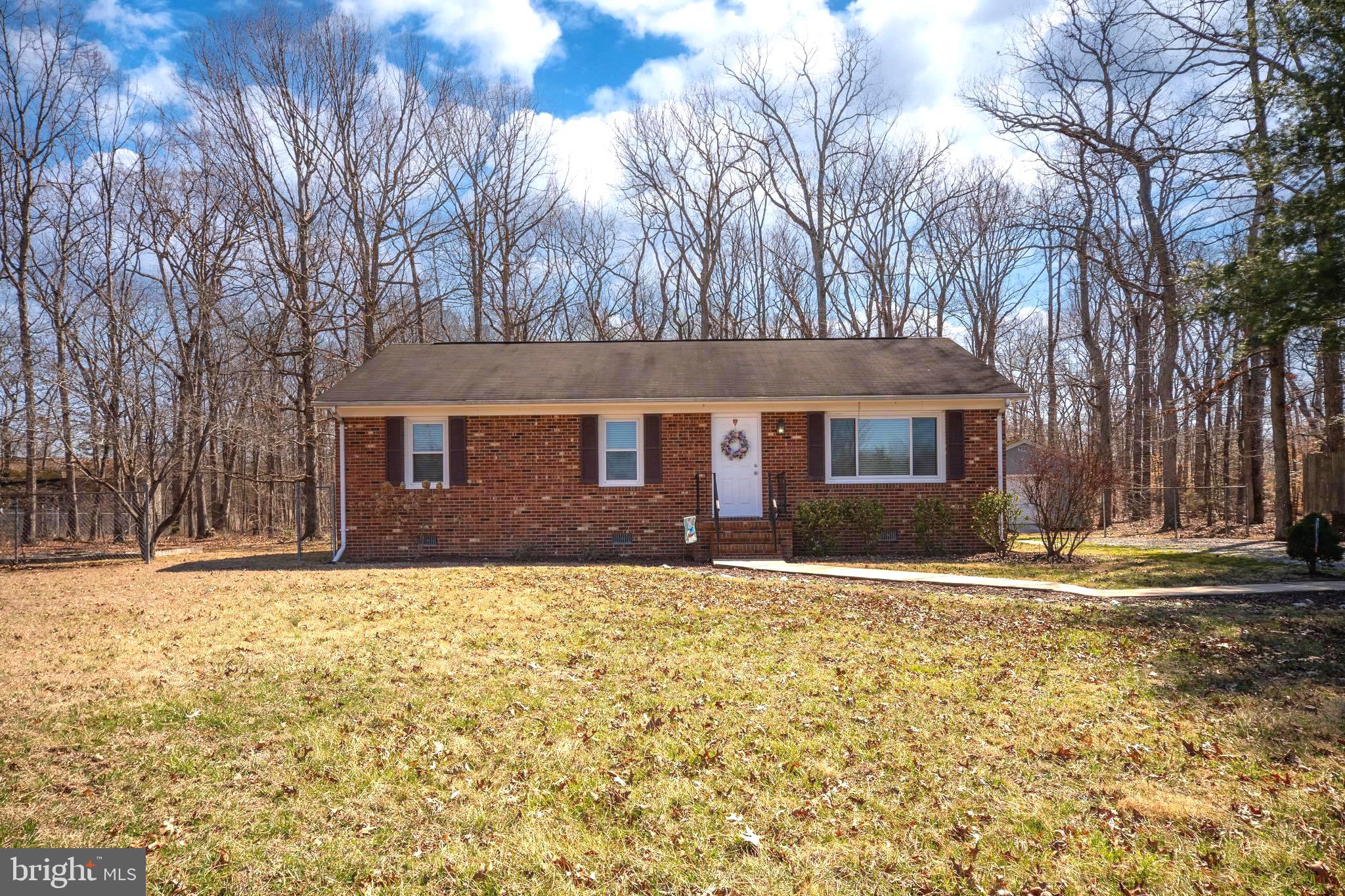 One-level living at its best with   NO HOA,   a large deck for entertaining and just over an acre of land!  This freshly painted home features 2 bedrooms, den with closet, 2 full baths, a large eat-in kitchen and a living room with a gas fireplace.  The primary bedroom offers its own full bath with a window for natural light, new LVP flooring, new cabinetry and a tub/shower combo.   The fully carpeted primary bedroom opens to a private sliding glass door leading out back onto the huge wooden deck.  The second full bath is updated with new LVP flooring, new cabinetry and a tub/shower combo.  The entire home has been freshly painted.  When you enter the front door sunlight blankets the living room through a huge picture window perfect for viewing breathtaking summer sunsets. On cold winter nights, you can look forward to relaxing by the corner fireplace.  Conveniently located right off of the living room, the kitchen and dining area, with warm wooden cabinetry, is easily accessible through the side entrance for the convenience of bringing your groceries directly into your kitchen.   All Whirlpool Stainless Steel Appliances (Fridge, Built-in Microwave, Dishwasher and Range/Oven); the included washer/dryer are tucked away with easy access in the kitchen.  The kitchen sink has a window above for natural light and a perfect view of your private tree lined backyard and large shed (as is) in good condition with lights and electric.  The home has a great eat-in kitchen with room for a table and yet another large sliding glass door off of the dining area leading out onto the huge wooden deck that runs the entire back length of your new home.  This home offers a private escape while still being conveniently located to I-95, a commuter lot (only 2.7 miles away), the VRE - Spotsylvania Station, grocery stores, shopping, Patriot Park and the YMCA.  You will have plenty of yard for all your summer outside play and entertaining.   High Speed Internet from Verizon and Xfinity is available.