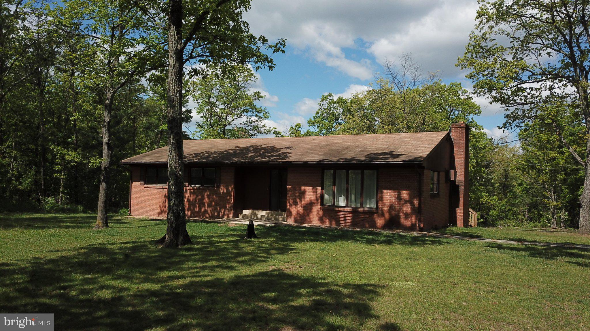 This charming ranch-style three-bedroom home offers a perfect blend of comfort and country chic elegance. This residence spans 1,690 square feet and sits on a generous 5-acre lot, offering ample space for outdoor activities and relaxation. The exterior, crafted from durable brick, exudes timeless appeal, while the landscaping and mature trees create a picturesque setting that enhances the property's natural beauty. 

Step inside to discover a thoughtfully designed interior that features a traditional floor plan, ideal for both entertaining and everyday living. The inviting dining area, complete with a wood-burning fireplace perfect for gathering on those cooler evenings for dinner or game night, seamlessly connects to the country-style kitchen, where culinary enthusiasts will appreciate the classic charm and functionality. 

Step outside onto the large deck, where you can enjoy the peaceful sounds of nature. This outdoor space is perfect for hosting summer barbecues or simply unwinding with a good book while surrounded by the beauty of your wooded lot. 

The property includes a detached garage with a wood-burning stove, perfect for those man-cave or she-shed seekers, and additional storage space, providing ample room for vehicles and all your outdoor toys and equipment. 

Located a short drive from Winchester, VA, or Berkeley Springs, WV, the property offers rural tranquility without sacrificing access to city amenities, making it a great value for buyers seeking space and convenience. 

Come check it out before it’s gone. Priced to reflect the need for some updating, this home offers opportunities for cosmetic improvements and personalization while remaining move-in ready for those who prefer to take on projects gradually. And to get you started, the Seller is offering a $3,000 credit with an acceptable offer to assist with carpet replacement, giving buyers the opportunity to personalize the home and begin updates to match their own style.
