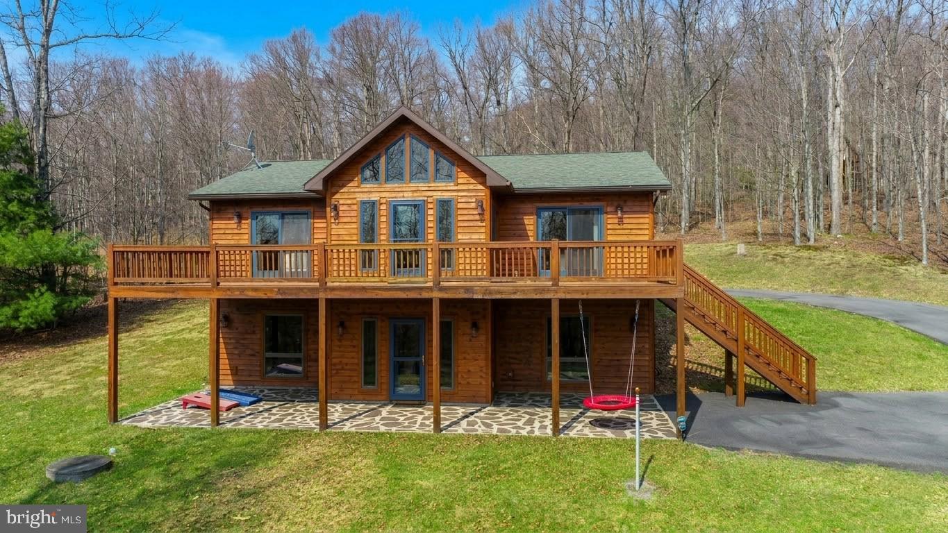 Log-style cabin in Sun View Heights, just minutes from Deep Creek Lake, Wisp Resort, and area amenities. Set on 1.03 wooded acres backing to trees, this 4-bedroom, 3-bath home offers 2,688 finished square feet across two levels. The main floor features an open layout with hardwood floors, a kitchen with an island and breakfast area, and a living room centered around a gas fireplace with natural light throughout.
The walk-out lower level adds a large rec room with wet bar and second gas fireplace, creating a comfortable second living space. Three bedrooms and two full baths sit on the main level, including the primary suite, while the lower level adds a fourth bedroom and full bath. Outdoor features include deck and patio space to enjoy the private wooded setting and seasonal lake views! Detached one-car garage and driveway parking. Minutes from DLC's premiere lakeside Golf at Thousand Acres. A well-rounded mountain home close to the best of Deep Creek Lake. Call today for details.