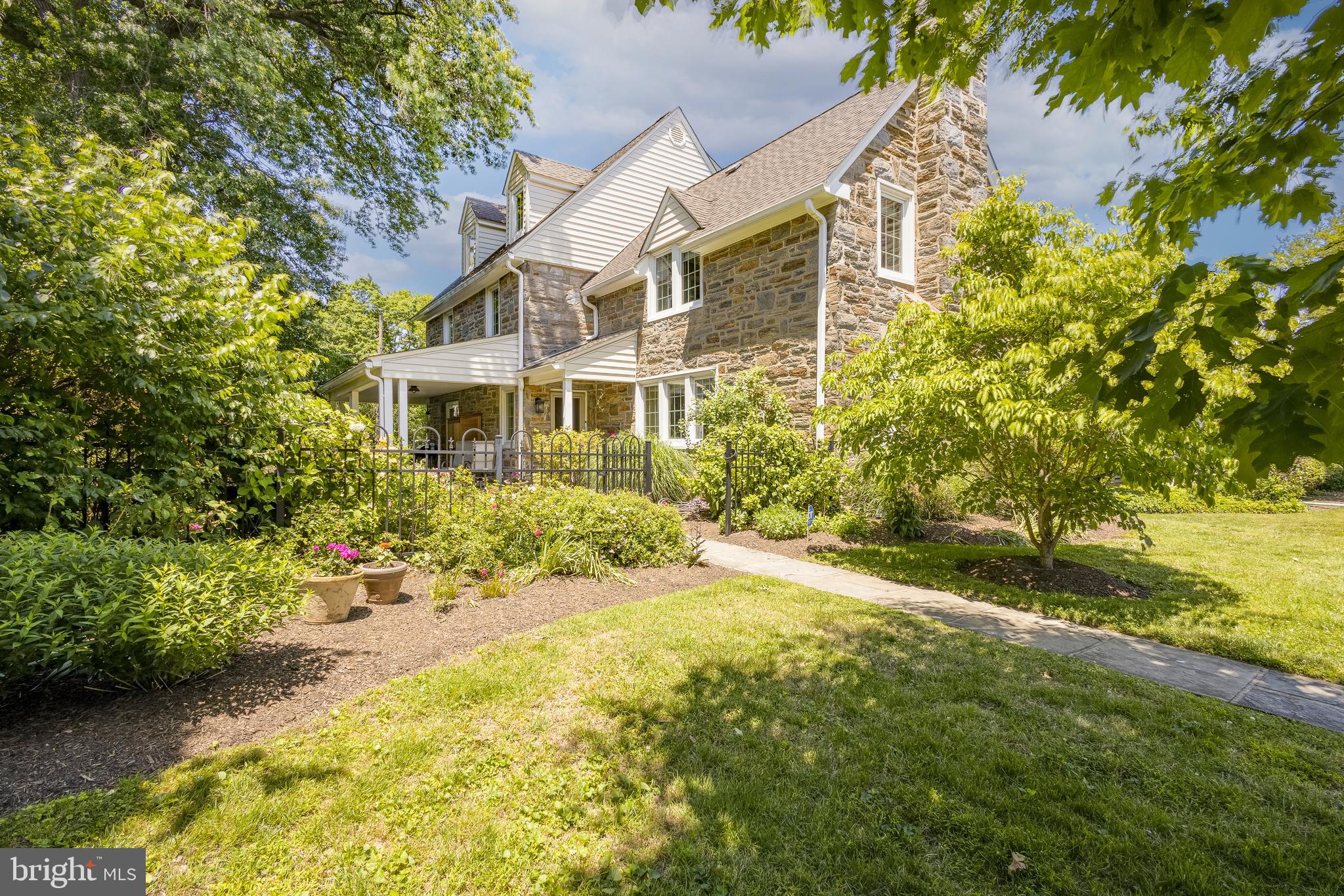 Welcome to 324 Holmecrest Road, a timeless stone Colonial nestled on a picturesque tree-lined street in one of Jenkintown's most sought-after neighborhoods. Rich in character, craftsmanship, and architectural charm, this exceptional 5-bedroom, 3.5-bath residence seamlessly blends classic elegance with thoughtful modern updates. From the moment you arrive, the home's striking stone façade, mature landscaping, and inviting presence set the tone for what awaits inside. Beautiful hardwood floors flow throughout the home, complemented by updated windows that fill each room with natural light while preserving the property's historic character. Every space reflects a remarkable attention to detail, from the original millwork and charming architectural accents to the carefully maintained finishes throughout. The spacious first floor offers gracious living and entertaining spaces, including an expansive living room, formal dining room, dedicated office, and a beautifully updated kitchen with adjoining breakfast area. Upstairs, the second and third floors provide five generously sized bedrooms and three full baths, offering flexibility for guests, home offices, or growing households. The finished lower level creates the perfect recreation room, media space, playroom, or fitness area, while still providing ample storage. Step outside to discover a private fenced yard surrounded by lush gardens and mature plantings. Whether you're enjoying morning coffee on the patio, entertaining friends, or tending to the garden beds, this outdoor oasis offers beauty and tranquility throughout the seasons. A detached two-car garage adds convenience and additional storage. Ideally situated within walking distance of the scenic trails and open spaces of Alverthorpe Park and the cultural destination of Abington Art Center, this home also places you moments from beloved local favorites including Drake Tavern, Trader Joe's, Whole Foods Market, and Gaul & Co. Malthouse.