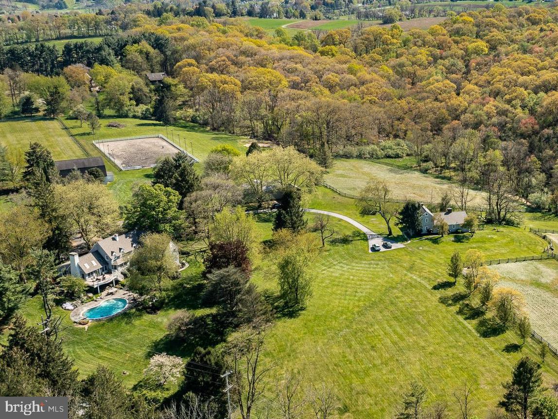 This marvelous property is uniquely set on 16+ acres abutting the 1,282 acre ChesLen Preserve. This
sought after location has it all – beautiful views, protected open space, quiet road, Unionville Schools, and
easy access to amenities. Features of the property include a spacious 4 bedroom, 5.1 bath home, second
home/cottage with 3 bedrooms and 2 full baths, a nine-stall barn, 3-car detached garage, utility shed, pastures, pond, pool and much more! The current owner has totally redone the home with a Living Room, Dining Room and staircase that could have graced the pages of Architectural Digest! The Living Room has a cathedral ceiling with beautifully crafted wooden arched beams and a handsome stone fireplace that soars to the ceiling. The gracious curved staircase represents the epitome of fine craftsmanship. Note the magnificent reclaimed oak flooring. Several atrium doors open to an expansive deck that overlooks the in-ground pool and the countryside beyond. The Dining Area enjoys a cathedral ceiling and a bank of windows offering beautiful views of the property. Adjacent to the Living Room is a Sun Room with a wall of south facing windows. Currently used as an exercise area, this space would make a fabulous home office, library, or countless other uses. The chef in the family will love the large Kitchen offering an abundance of fine cabinetry, boundless granite counters, and high-end appliances including a Wolf gas range, two Wolf wall ovens, and a Miele dishwasher. Conveniently, next to the Kitchen is a Family Room with a back staircase and a wall of glass windows to embrace the wonderful views. The large Primary Suite offers two walk-in closets and a bathroom with a ball-and-claw soaking tub, heated floor, and an oversize shower. Two of the remaining bedrooms offer ensuite bathrooms and the fourth uses a nearby hall bathroom. The Lower Level of the home offers a second Family Room that is perfect for watching a movie or having friends over to see the big game. From here, there is direct access to a flagstone patio and the home’s in-ground pool. There is also a full bathroom and a unique exterior access that is perfect for those with wet bathing suites entering and exiting without having to walk through the Family Room. The Lower Level also hosts the home’s large Laundry area.
Equestrians will love the nine-stall barn and the multiple pastures. Additional farm amenities include a
detached three car garage and a large new Utility Shed, perfect for housing horse trailers, tractors and farm
equipment, or even a car collection. The fully updated and spacious cottage is perfect as a guest house,
family compound, or tenant house. This property represents a significant value and ideal living opportunity.