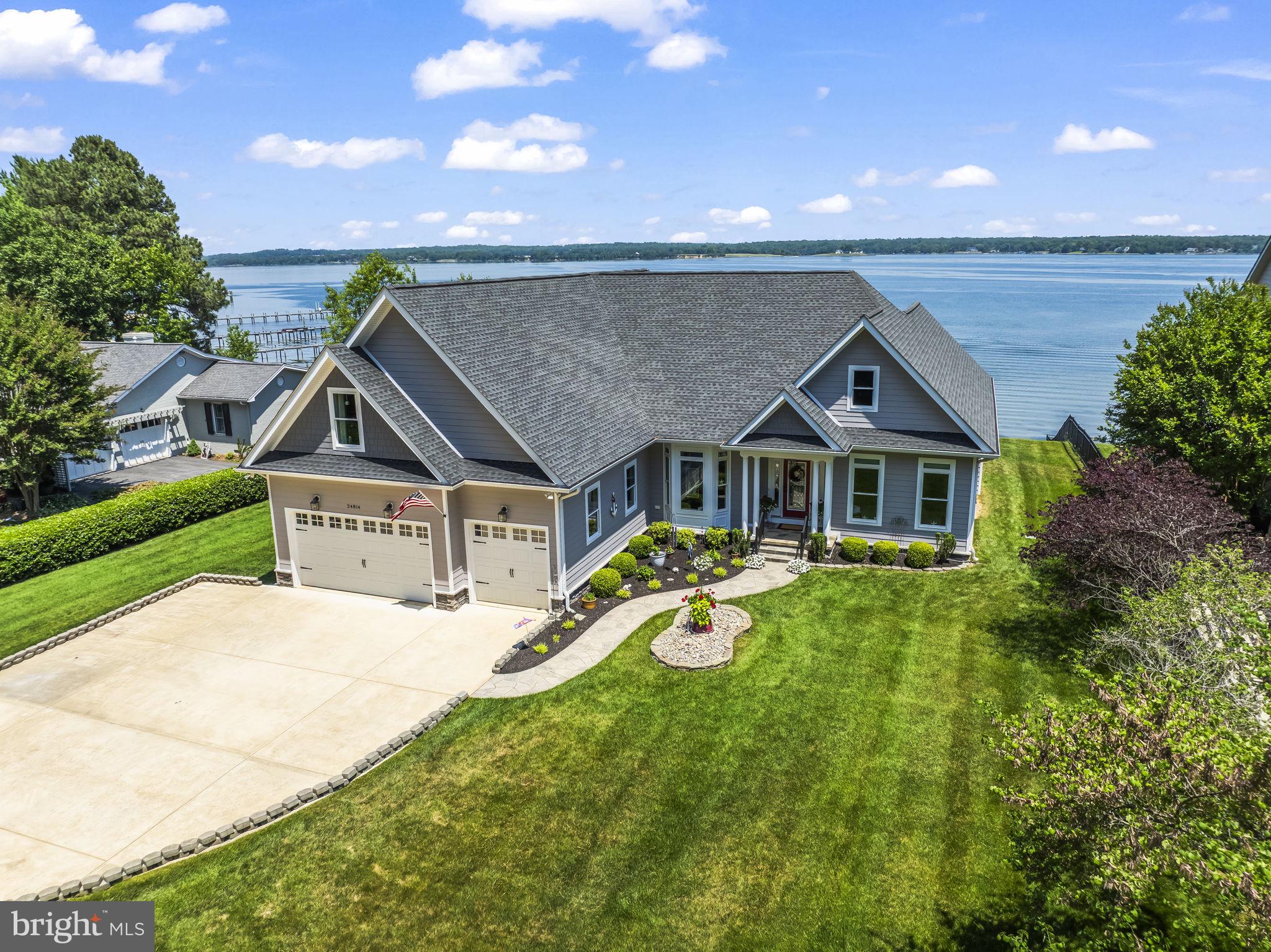 Welcome to this stunning custom waterfront home, situated high on Half Pone Point, offering elegant living on the St. Mary’s side of the Patuxent River. Built in 2014, this well-maintained property features quality workmanship throughout its approximately 4,500 square feet of above-grade living space. The bright and open interior features a first-floor owner's suite, spacious secondary bedrooms upstairs, and a large upper-level craft/media room. The main level offers 9' ceilings, hardwood floors, a dedicated office, dining room, and an inviting family room with a coffered ceiling, adjacent to a tile-floored sunroom to capture coastal scenery all year, complete with an indoor porch swing. The main-level primary suite boasts elegant tray ceilings and three expansive walk-in closets. The spa-like primary bath features a heated floor, a separate walk-in shower, dual vanities, a private water closet, and a luxurious two-person whirlpool tub, with convenient direct access to the spacious laundry room. The chef-inspired gourmet kitchen features stunning granite counters, custom 42" cabinetry, and a full suite of professional stainless steel appliances. Culinary enthusiasts will appreciate the gas cooktop with a dedicated pot filler and the large corner pantry. Transition seamlessly to the unparalleled outdoor oasis, designed for grand entertaining. The 14x20 composite deck features sleek glass railing panels for unobstructed views and a retractable awning for shade. Below, a hardscape patio defines a comfortable conversation area centered around a remote-controlled gas fire pit—ideal for enjoying cool coastal evenings. This is the epitome of coastal living, defined by exceptional waterfront amenities: 100 feet of private Patuxent River frontage, complete with a 290-foot pier and boat lift, providing effortless deep-water access to the Chesapeake Bay and stunning, direct views of the iconic Solomons Island Bridge. Ample storage and flex space abound, including an oversized 3-car garage, a dedicated RV pad, and a 16x10 Amish-built shed. The unfinished walk-up basement offers vast potential, complete with built-in shelving, a workbench, a convenient half bath, and an exterior entrance. Modern systems ensure year-round comfort and peace of mind, including a dual-zone HVAC system (heat pump with gas furnace backup) and a ready-to-use home generator. Built for enduring resilience and convenience, the home features durable HardiePlank siding and 30-year Timberline architectural shingles. Short commute to NAS Pax River, home of the US Naval Test Pilot School. Embrace the Southern Maryland lifestyle with immediate access to recreational boating, fishing, and crabbing. Explore nearby historic towns—Solomons, St. Mary’s City, and Leonardtown—offering fine dining, seasonal concerts, and festivals. It's your turn to claim this luxury retreat and coastal charm, entertaining friends and family along the picturesque shores of the Patuxent River.